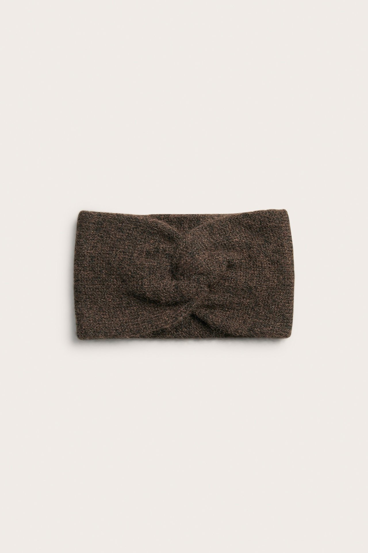 Framifrån en brun stickad hårband med knuten detalj.