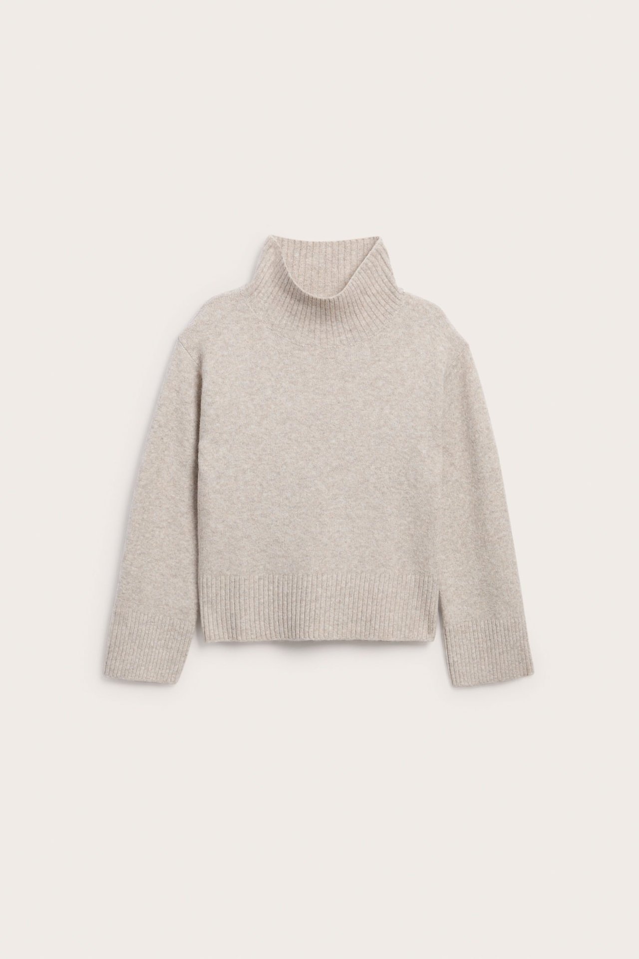Framsida av en ljusbeige stickad polotröja med ribbade muddar och nederkant.