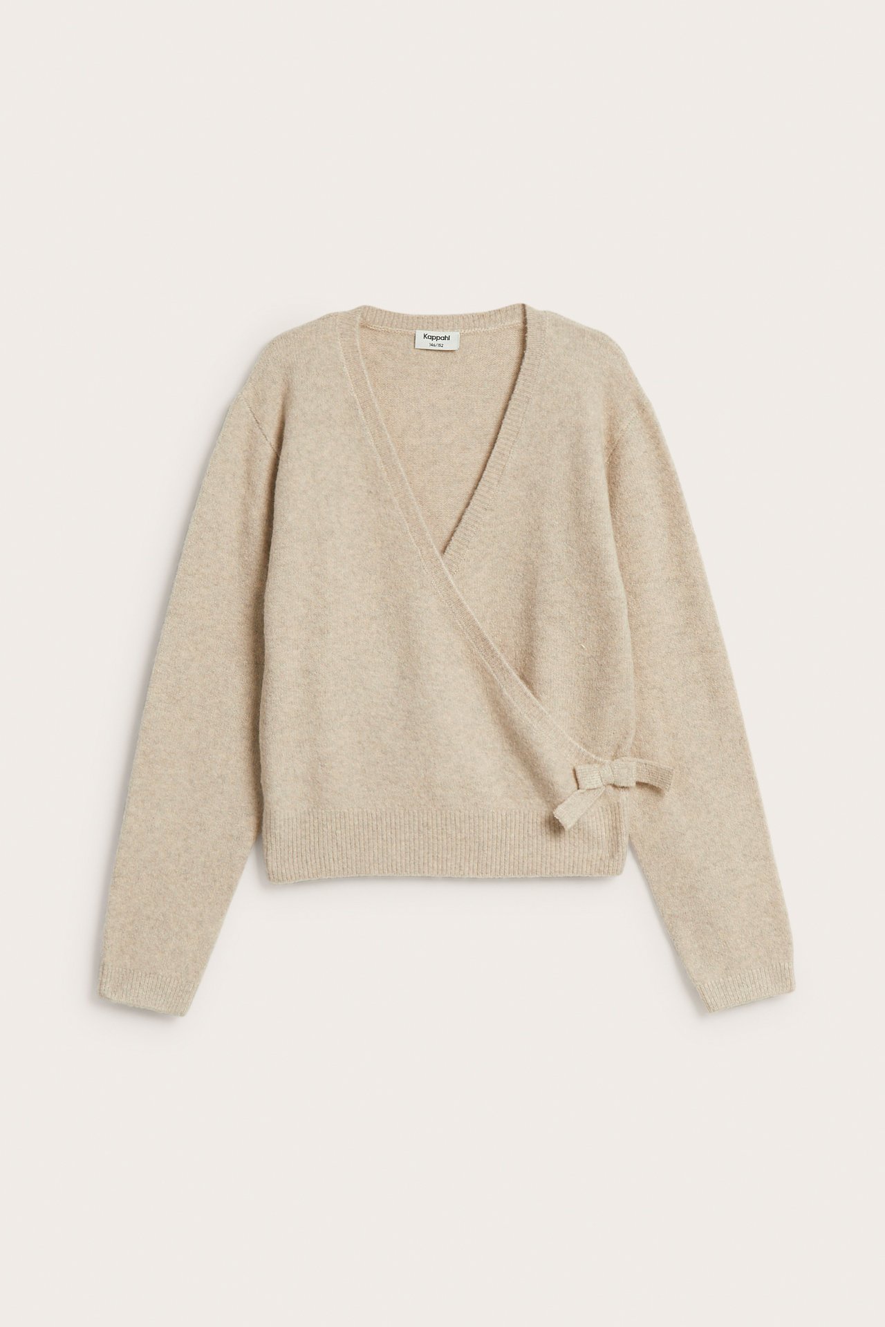 Framsida av en ljusbeige stickad omlottkofta med en rosettdetalj på sidan.