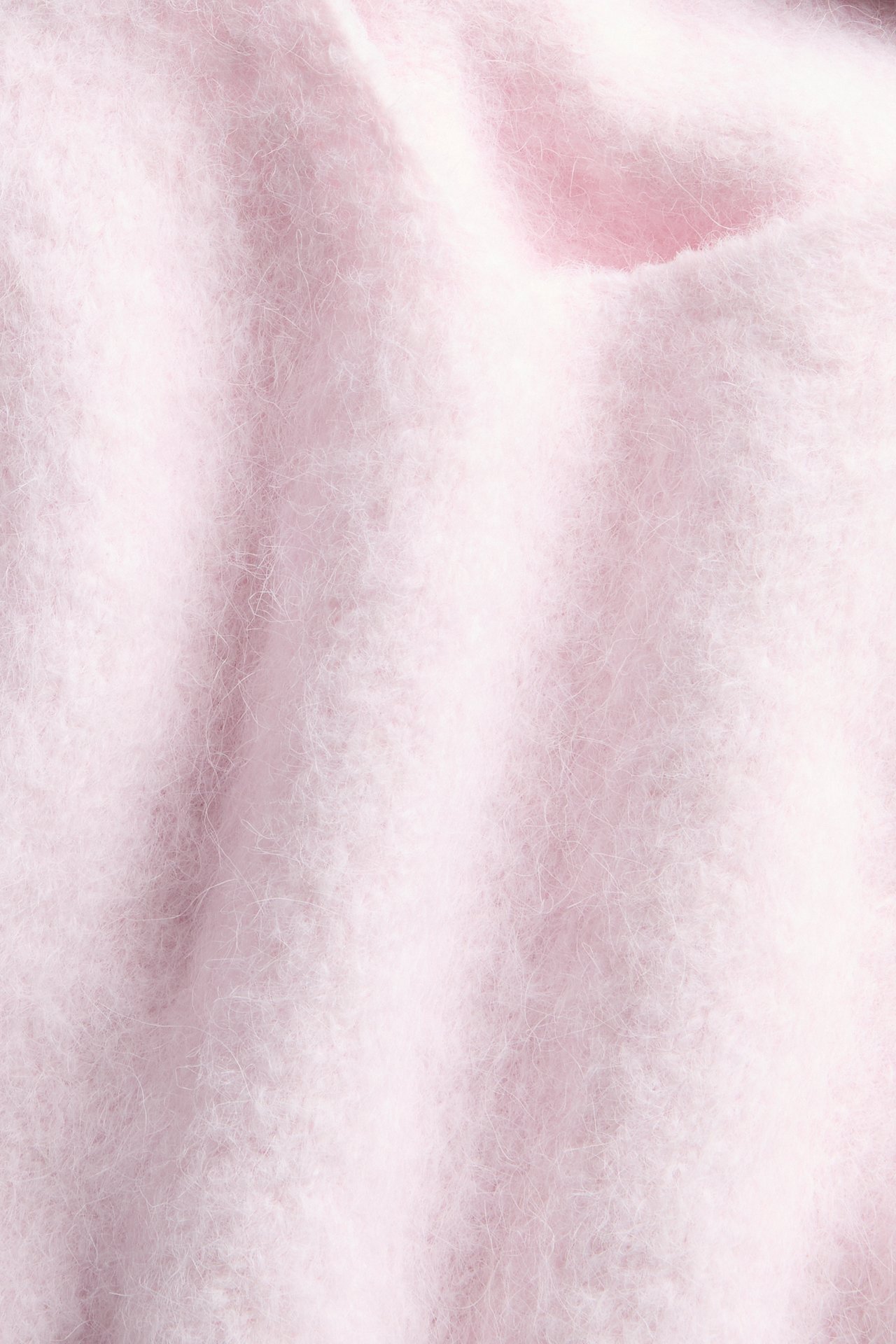 Närbild av ett rosa, mjukt, luddigt stickat tyg.