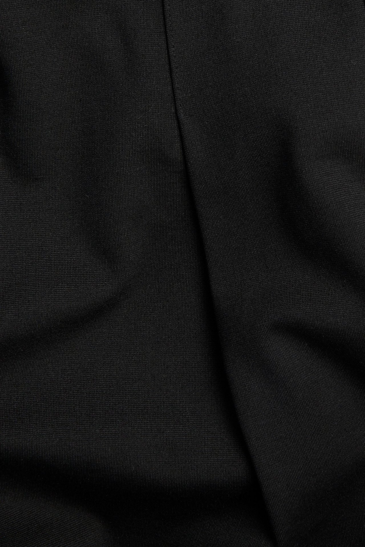 Lähikuva mustasta yksivärisestä paksusta trikookankaasta, jossa on hienovaraisia laskoksia.