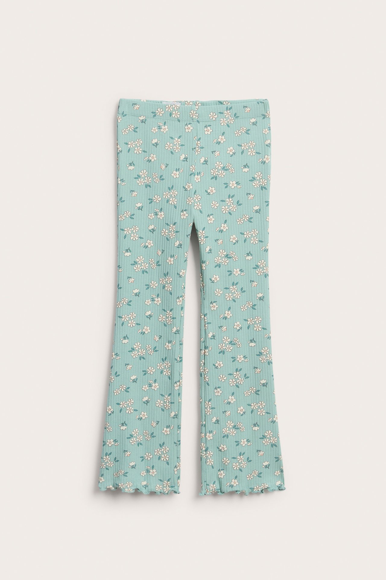 Framsida: barnbyxor med ribbad ljusgrön blommig design och utsvängda ben med vågig kant.
