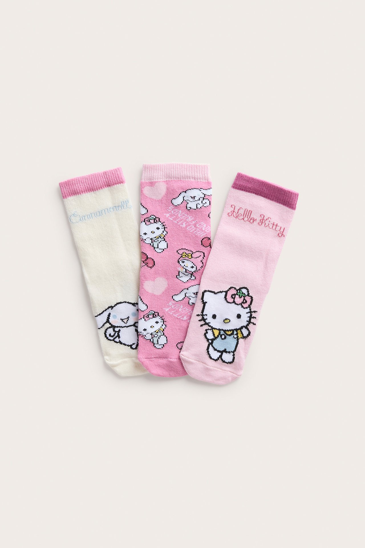 Kolme paria lastensukkia: vaaleanpunainen Hello Kitty, kuvioitu vaaleanpunainen ja luonnonvalkoinen Cinnamoroll.