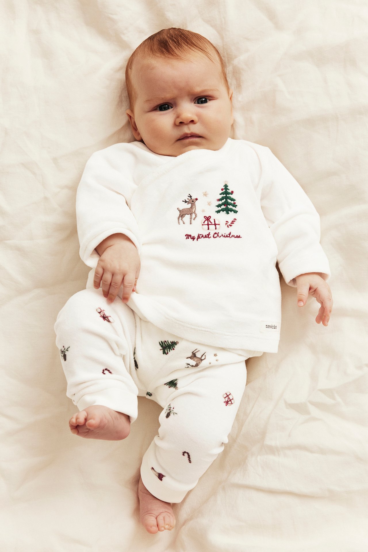 Ovenfra: baby i hvit 'My first Christmas' brodert topp og matchende mønstrede bukser.