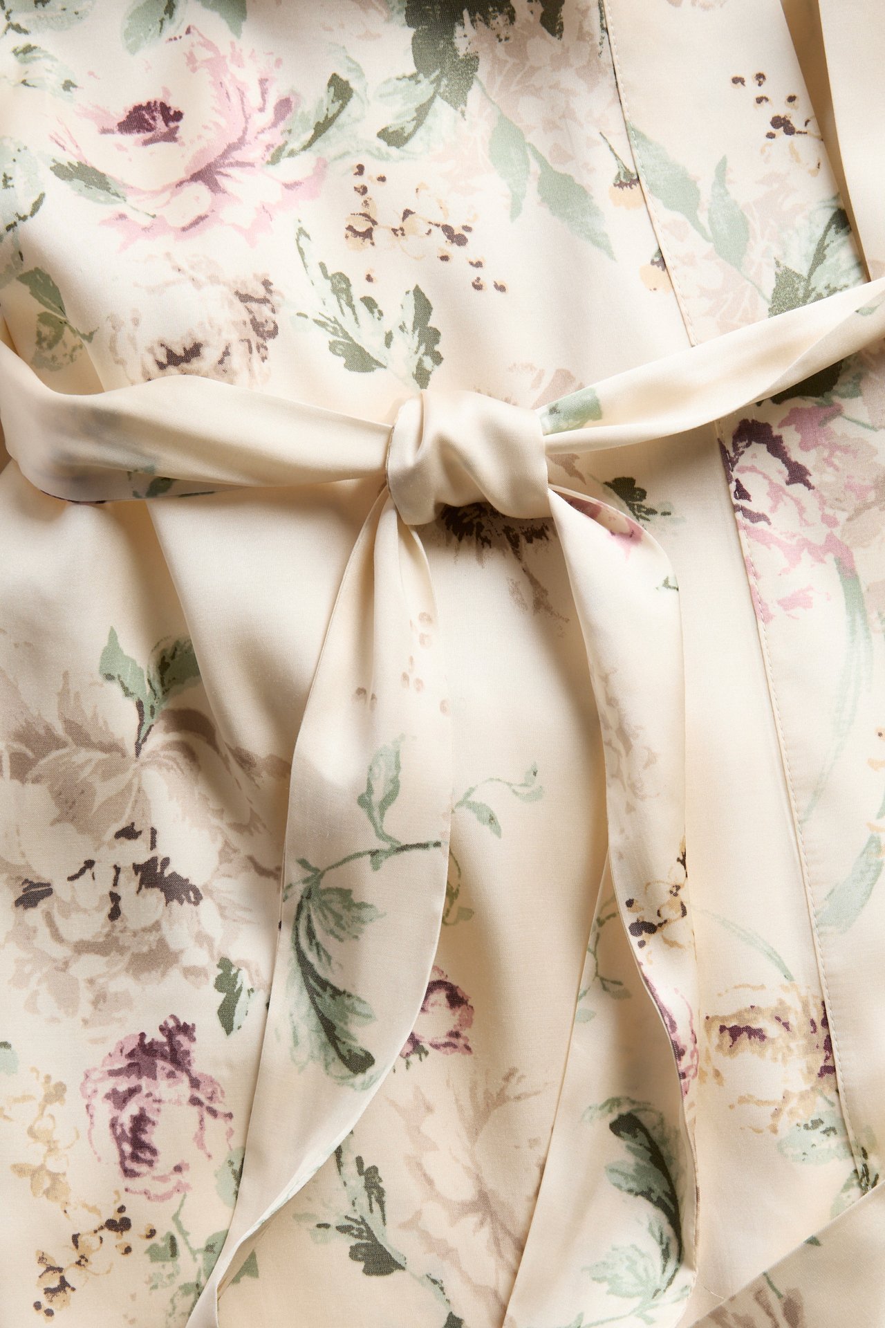 Zbliżenie z przodu na ecru satynowy szlafrok kimono w kwiaty z wiązanym paskiem.