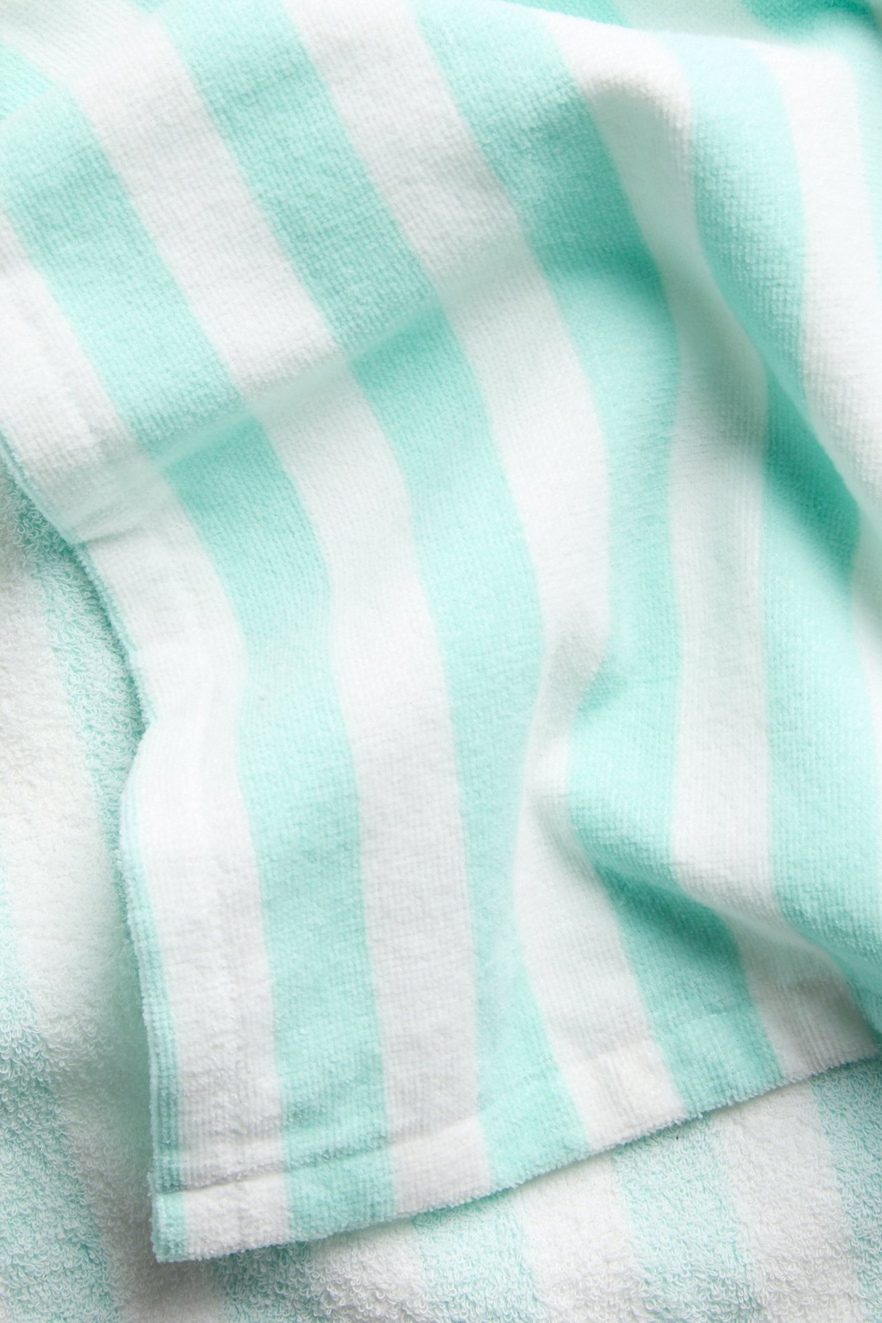 Lähikuva mintunvihreästä ja valkoisesta raidallisesta puuvillafrotee-uimaponchosta.