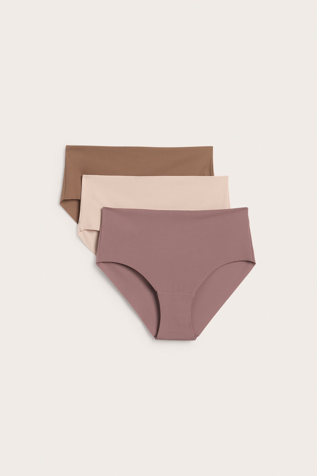 Edestäpäin kolme naisten korkeavyötäröistä alushousuparia: vanha roosa, beige ja ruskea.