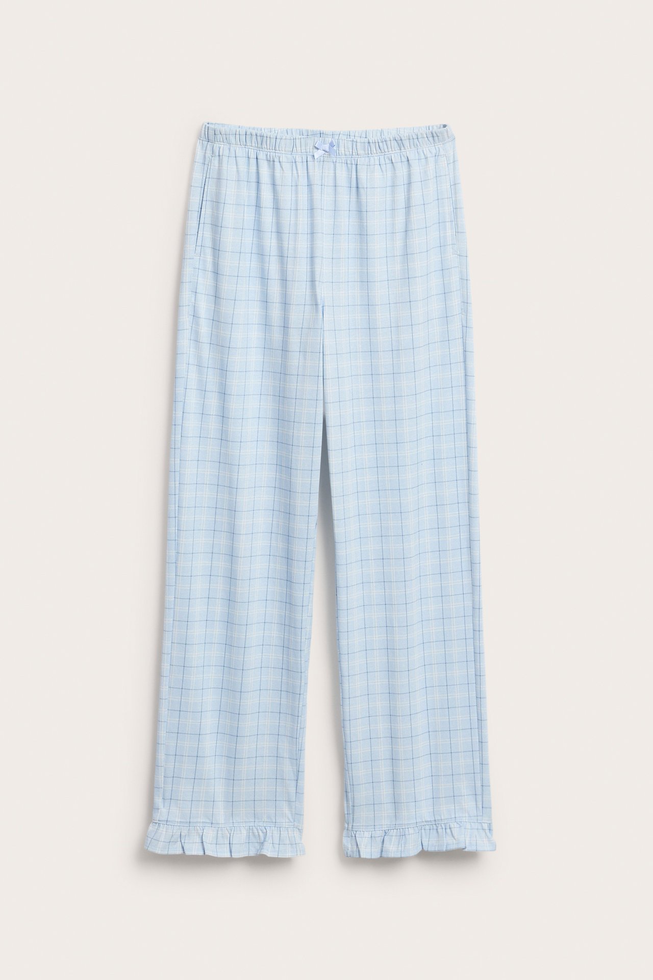 Frontvisning av lyseblå rutete jersey-pyjamasbukser med elastisk midje, snøring, lommer og volangkant.