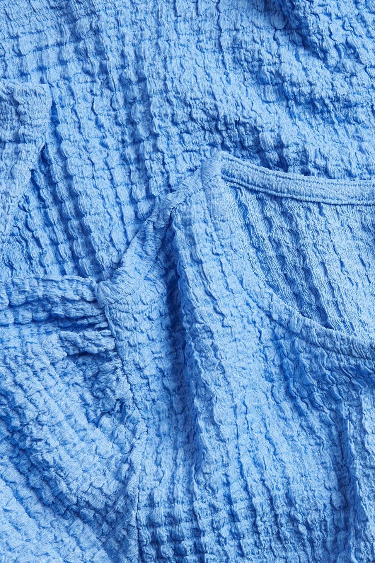 Lähikuva vaaleansinisestä lyhythihaisesta topista, jossa on strukturoitu kangas.