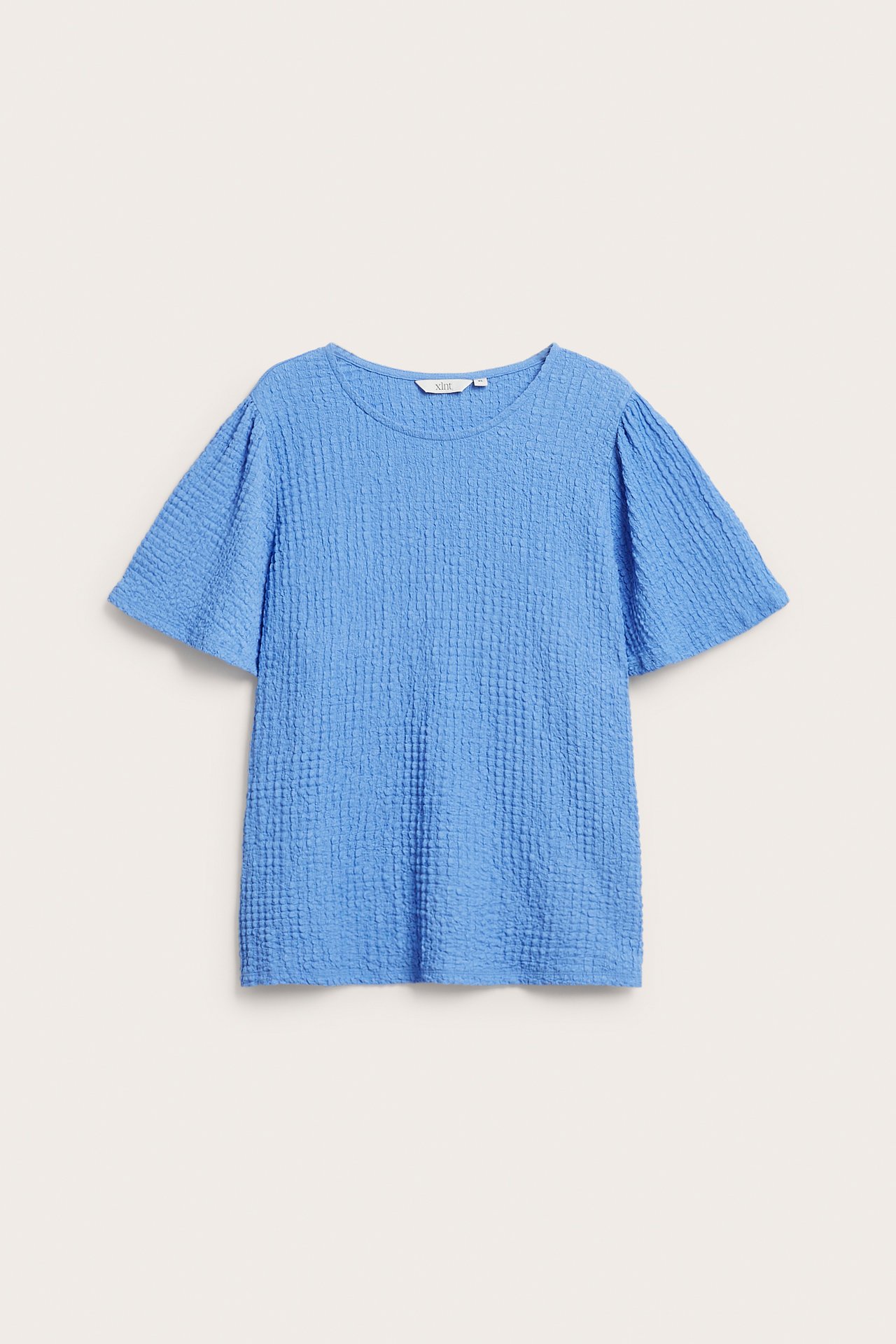 Edestä, sininen lyhythihainen toppi, jossa on pyöreä pääntie ja rakenteellinen, yksivärinen kangas.