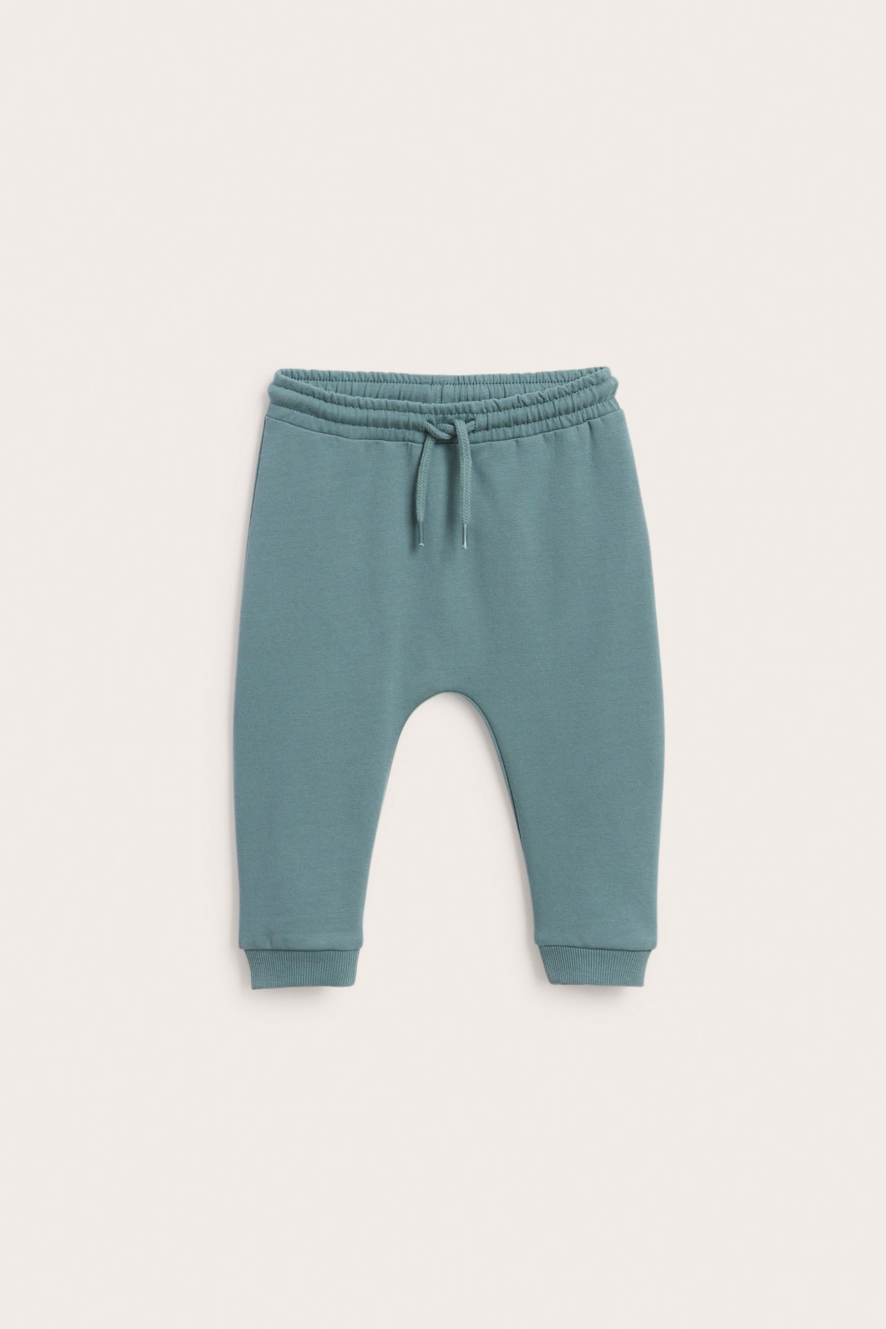 Framsida av teal babyjoggers med resår och dragsko i midjan samt ribbade muddar.