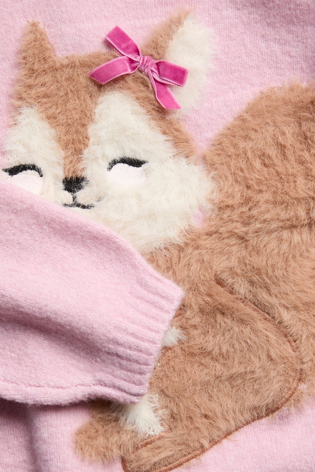 Närbild av en rosa fluffig barntröja med en ekorreapplikation som bär en rosa rosett.