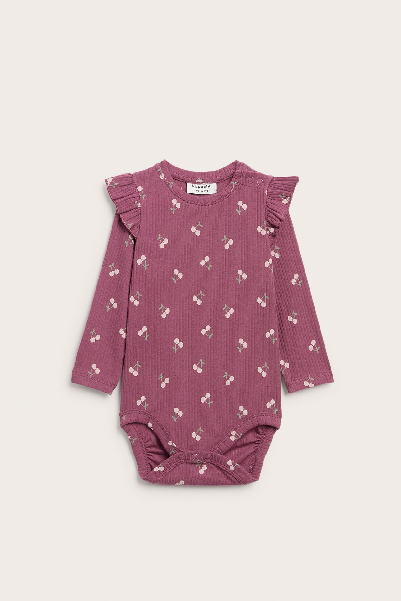 Framifrån, en plommonfärgad ribbad långärmad babybody med volanger och vitt körsbärsmönster.