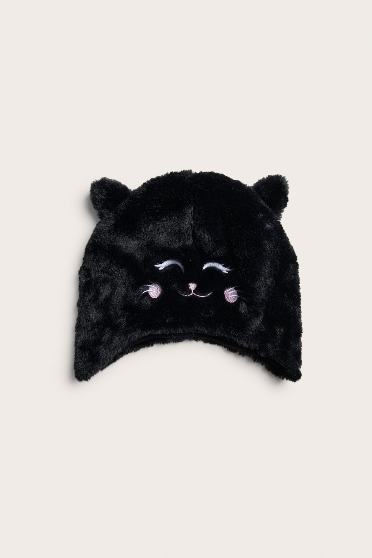 Frontvy av en svart fluffig katthatt med broderade sovande ögon, nos och rosiga kinder.