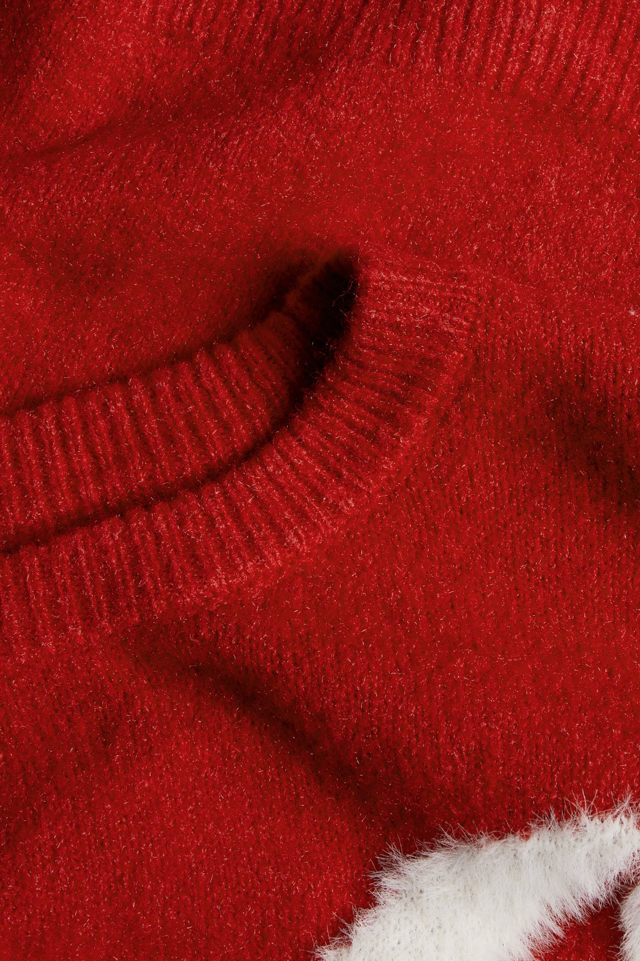 Zbliżenie na czerwony puszysty sweter z prążkowanym okrągłym dekoltem i białym puszystym detalem.