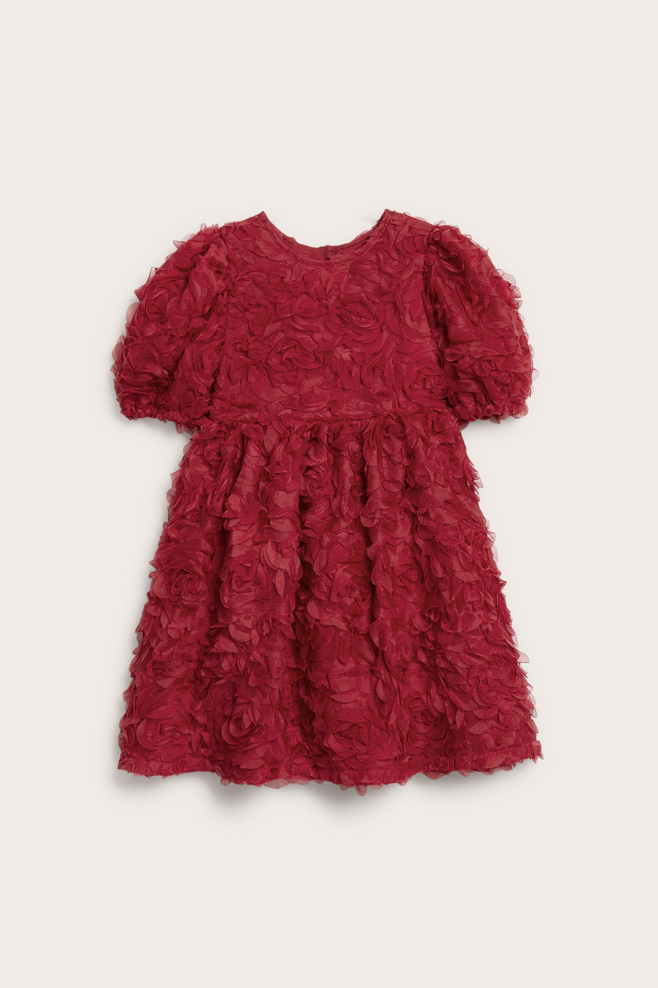 Widok z przodu krótkiej czerwonej sukienki dziecięcej z bufiastymi rękawami i fakturą 3D w kwiaty.