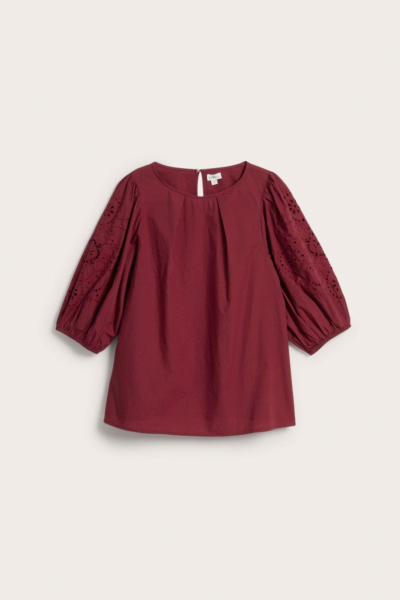 Forfra, burgunder bluse med rund hals og broderte 3/4 puffermer med hullmønster.