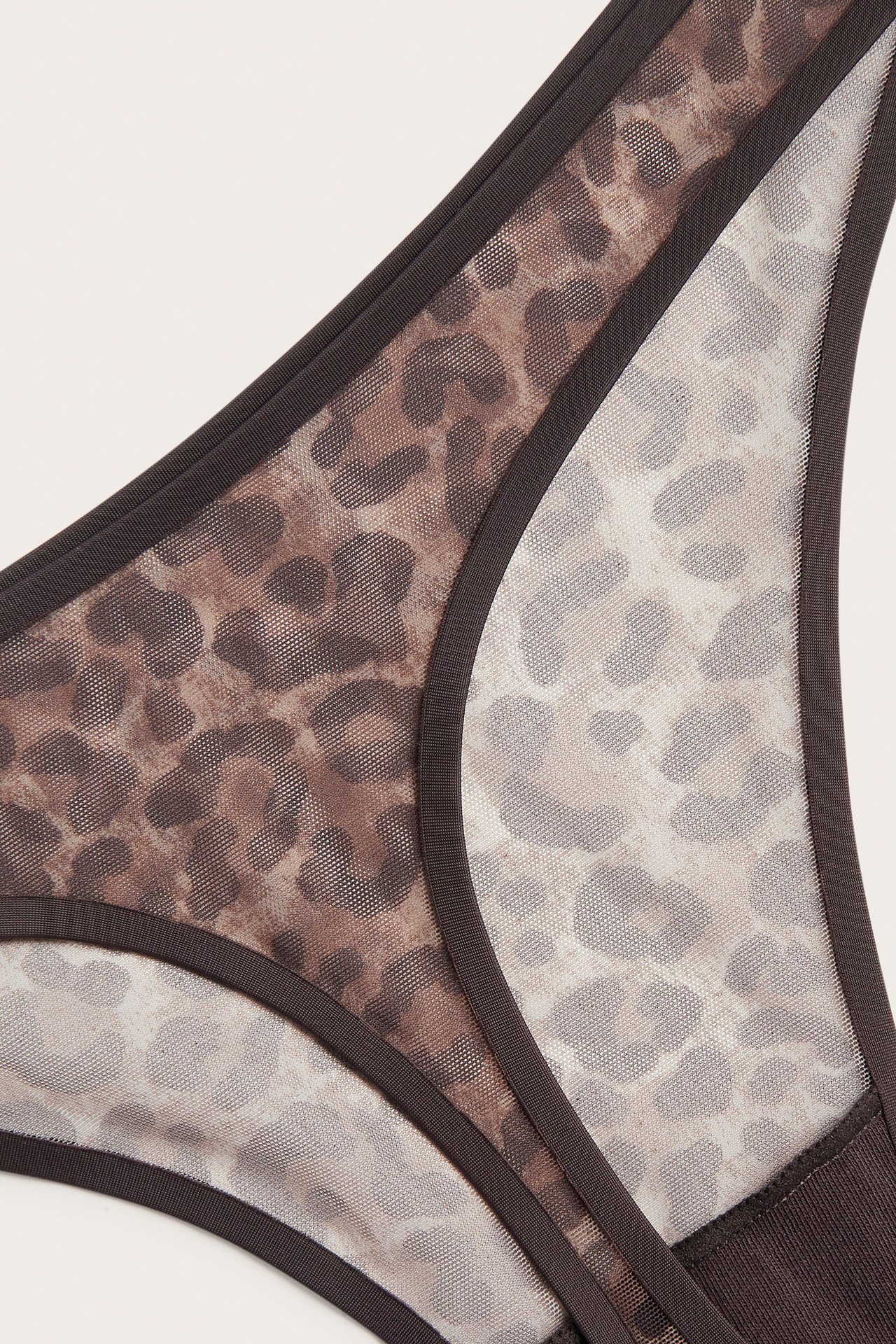 Nærbilde av brun og beige leopardmønstret mesh-truse med mørkebrun kant.