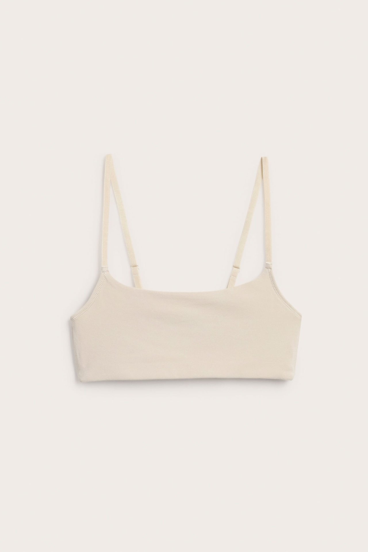 Frontbilde av en ensfarget beige square-neck bralette med tynne justerbare stropper.