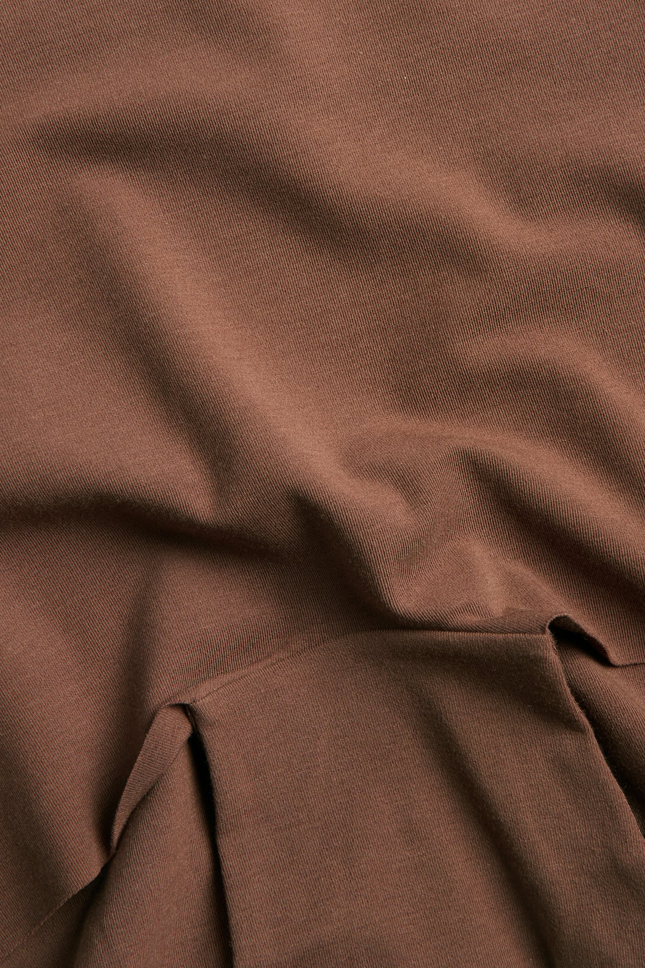Närbild av brunt texturerat tyg med mjuka veck.