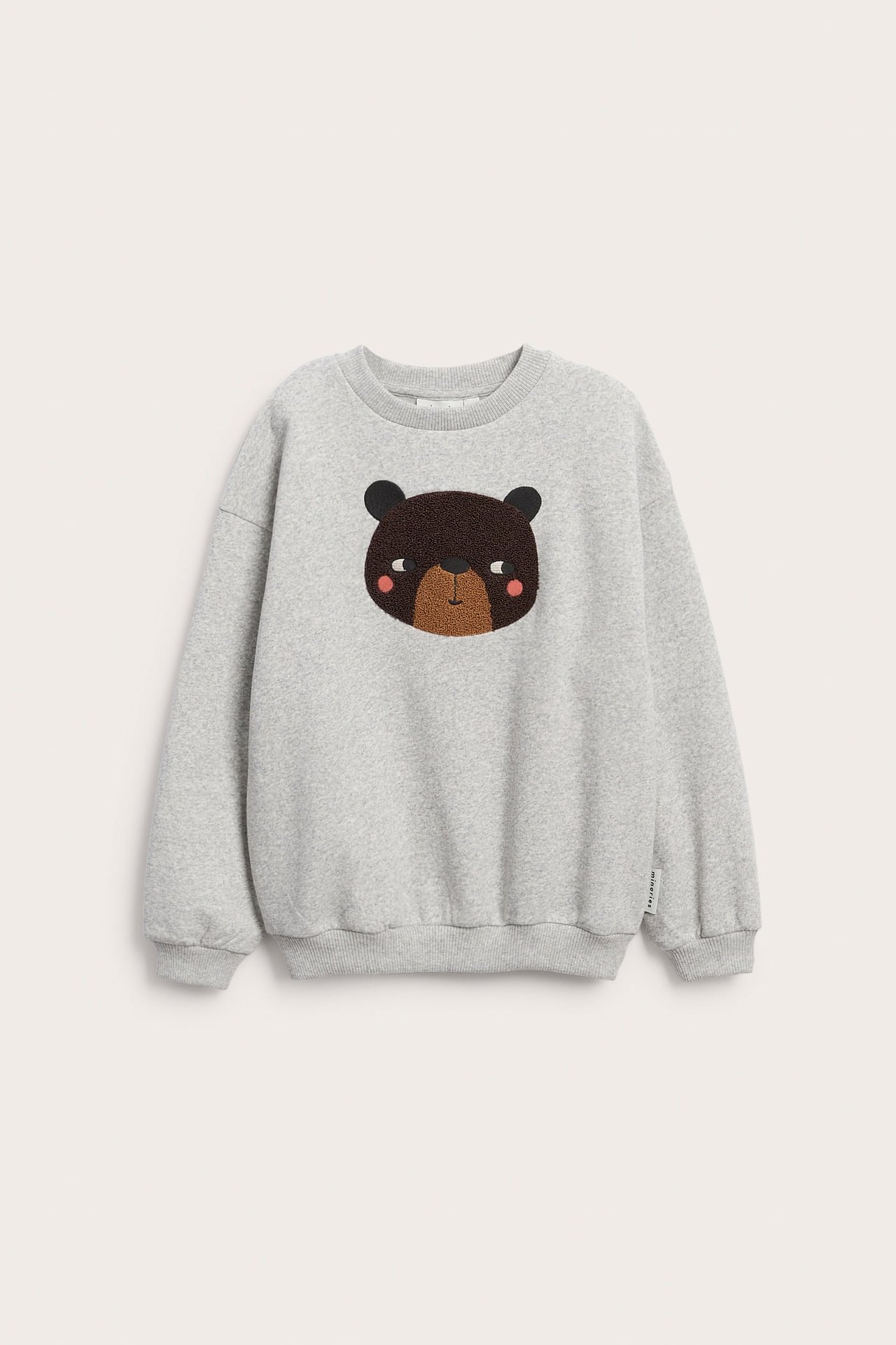 Forfra, lysegrå barnesweater med brodert brunt bjørneansikt.