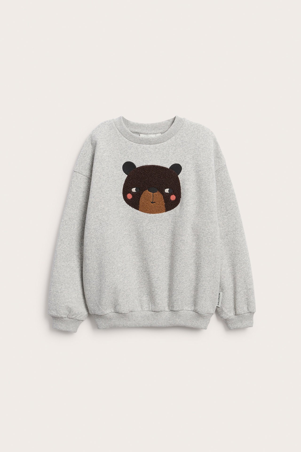 Forfra, lysegrå barnesweater med brodert brunt bjørneansikt.