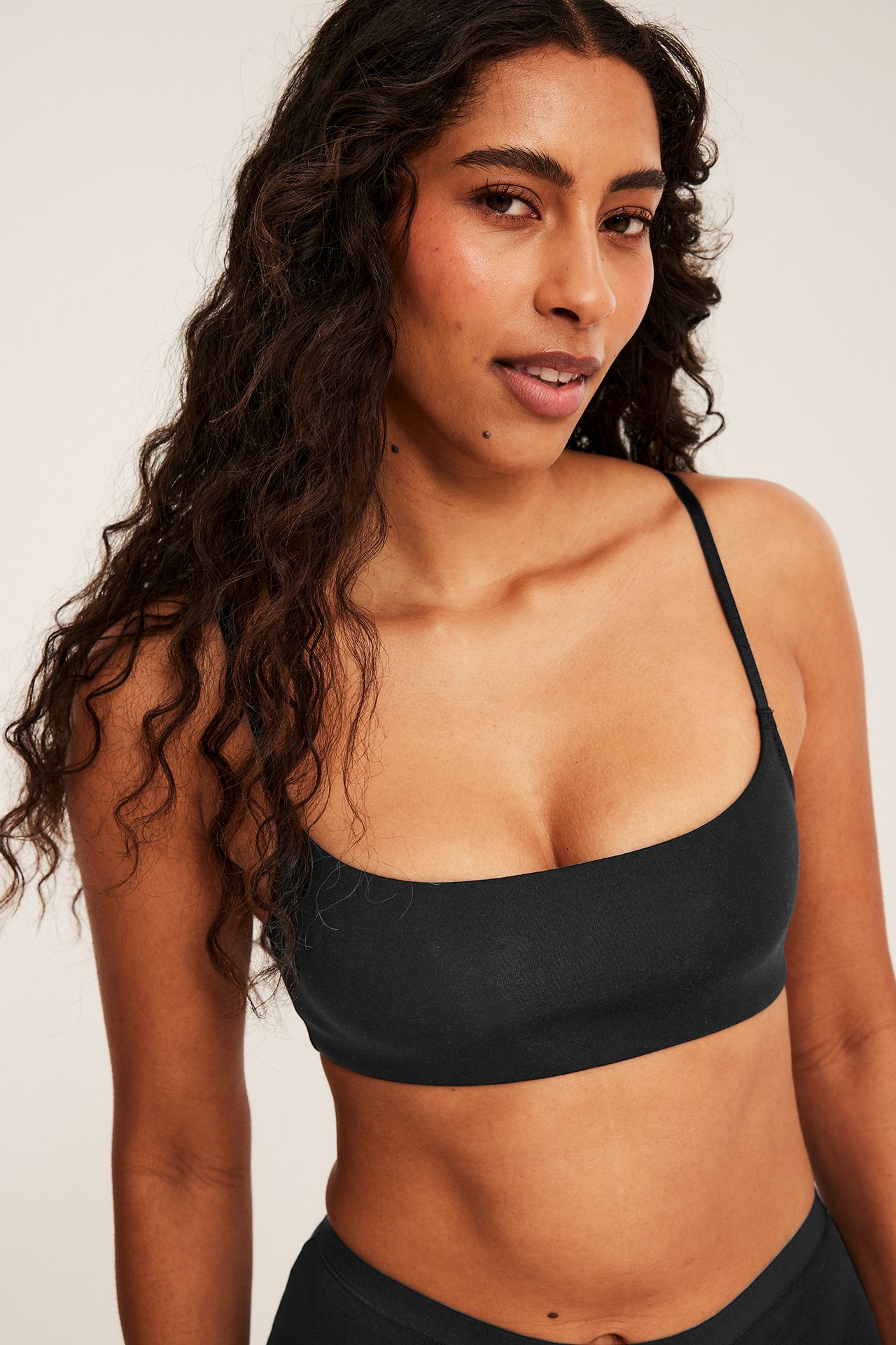 Framifrån, kvinnlig modell bär svart fyrkantig bralette och matchande underkläder.