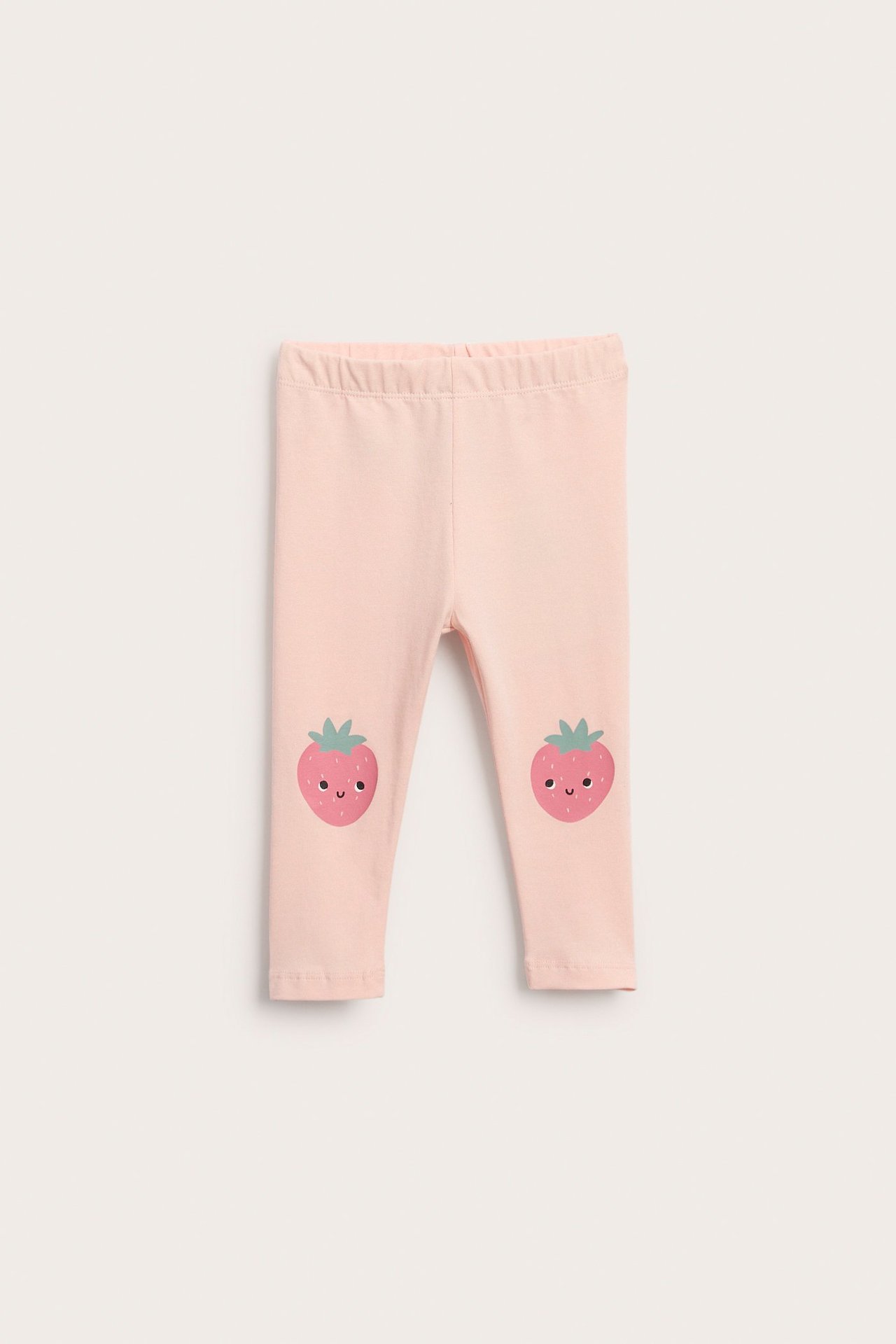 Widok z przodu, jasnoróżowe bawełniane legginsy niemowlęce z elastycznym pasem, truskawkowe nadruki na kolanach.