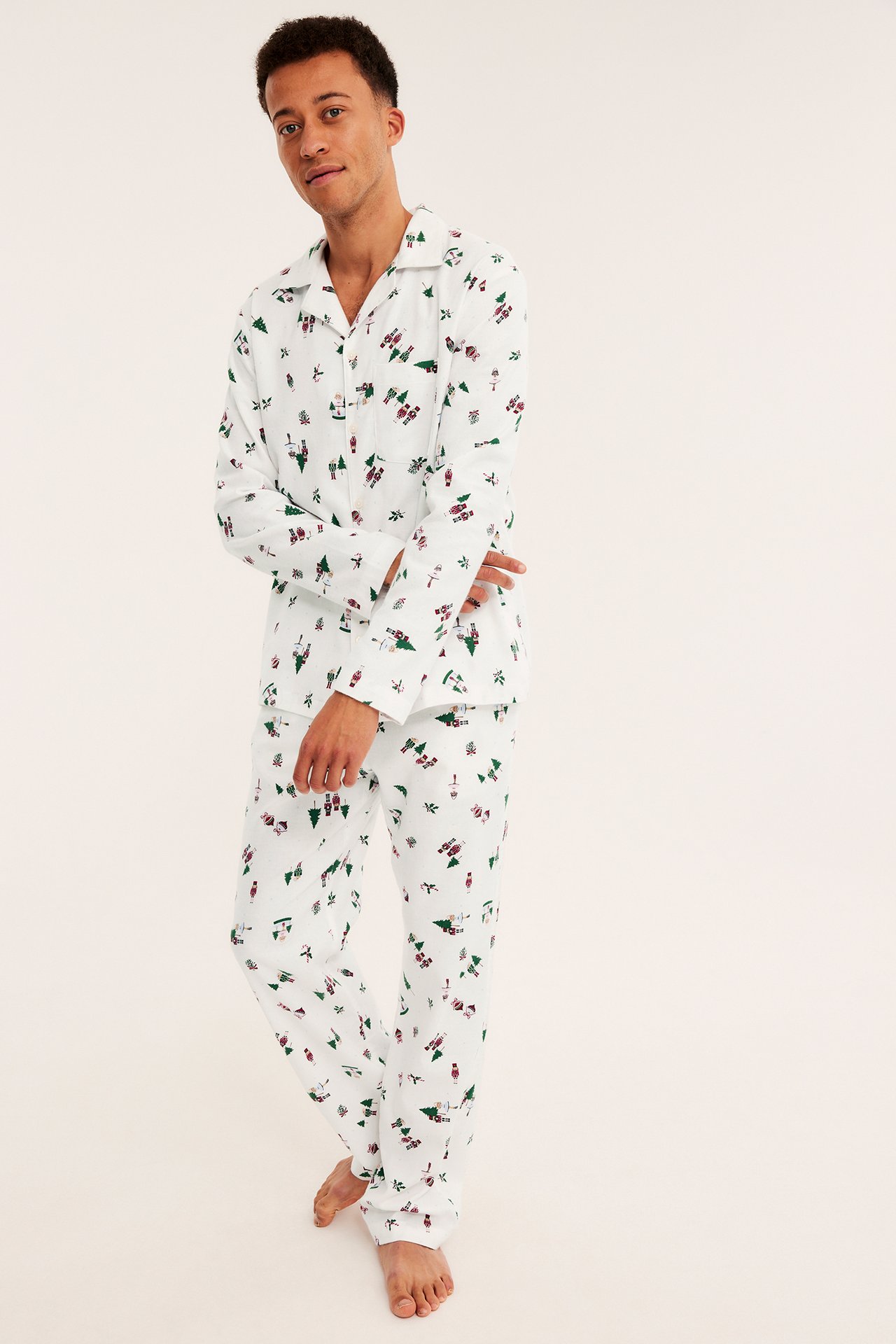 Framsida av man i vit tvådelad pyjamas med gröna julgranar och röda nötknäppare.