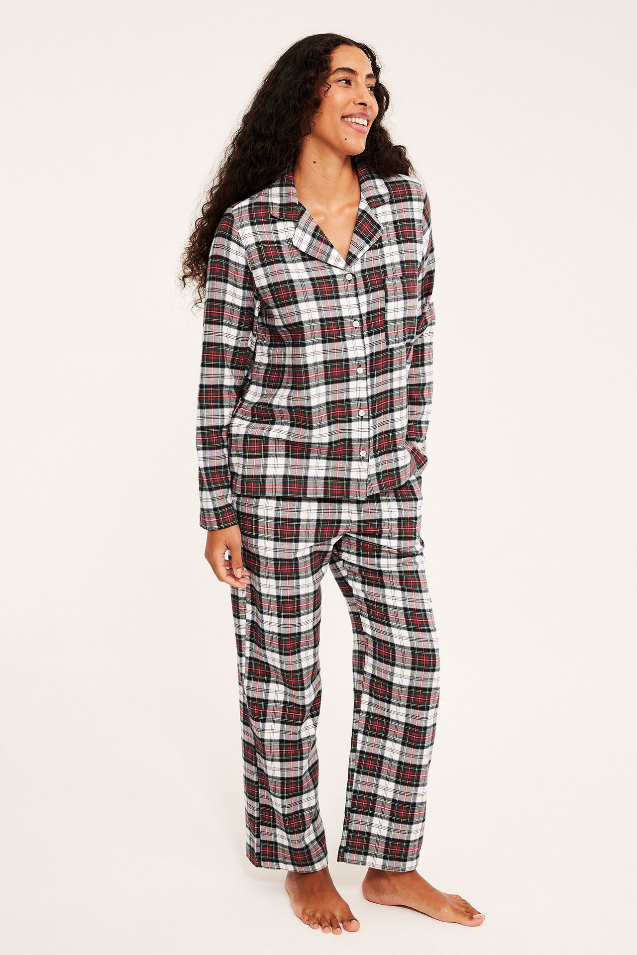 Edestä näkymä naismallista punamusta-valkoisessa ruudullisessa pyjamasetissä.
