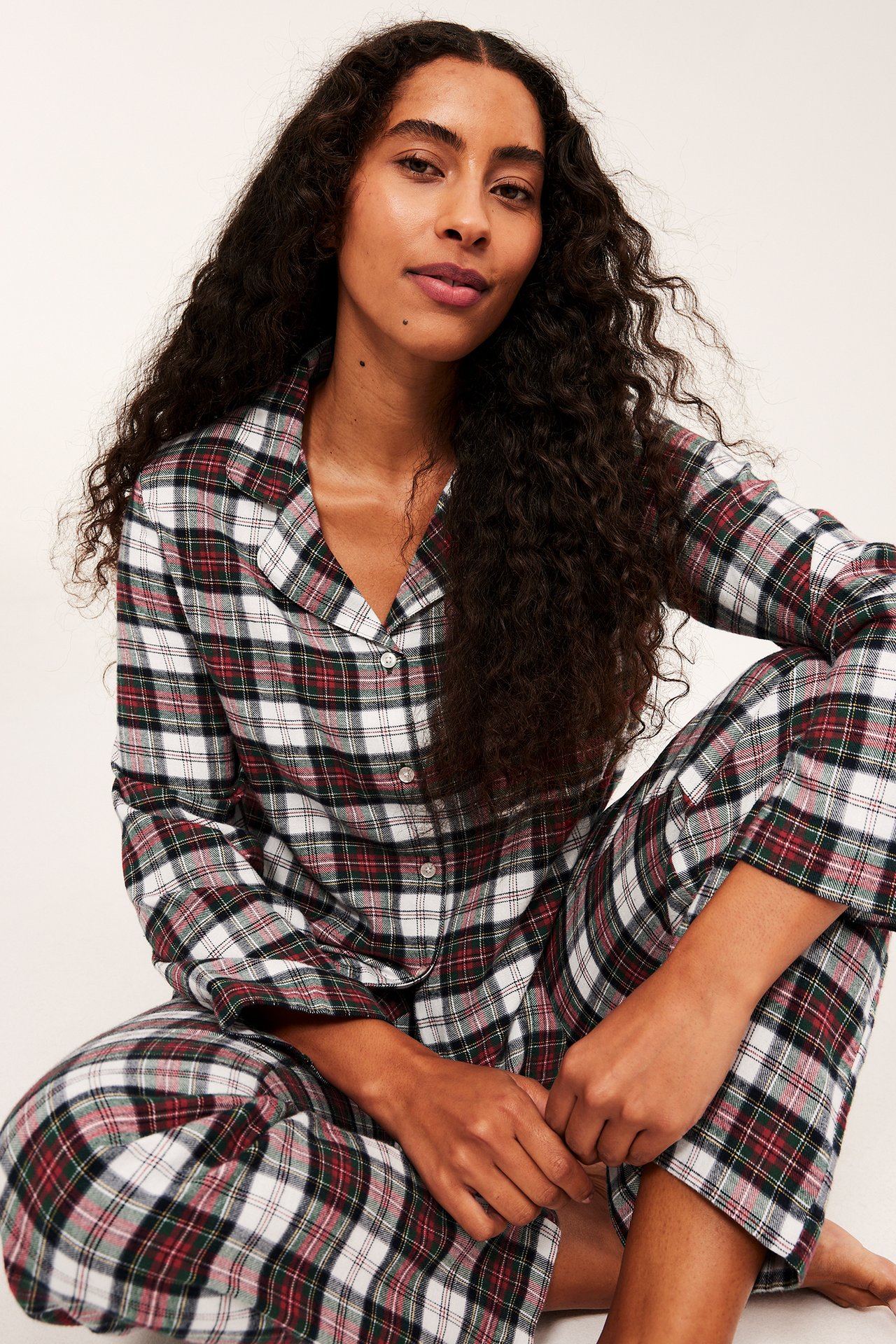 Frontvy av en vuxen kvinna i en vit, röd och mörkgrön rutig pyjamas.