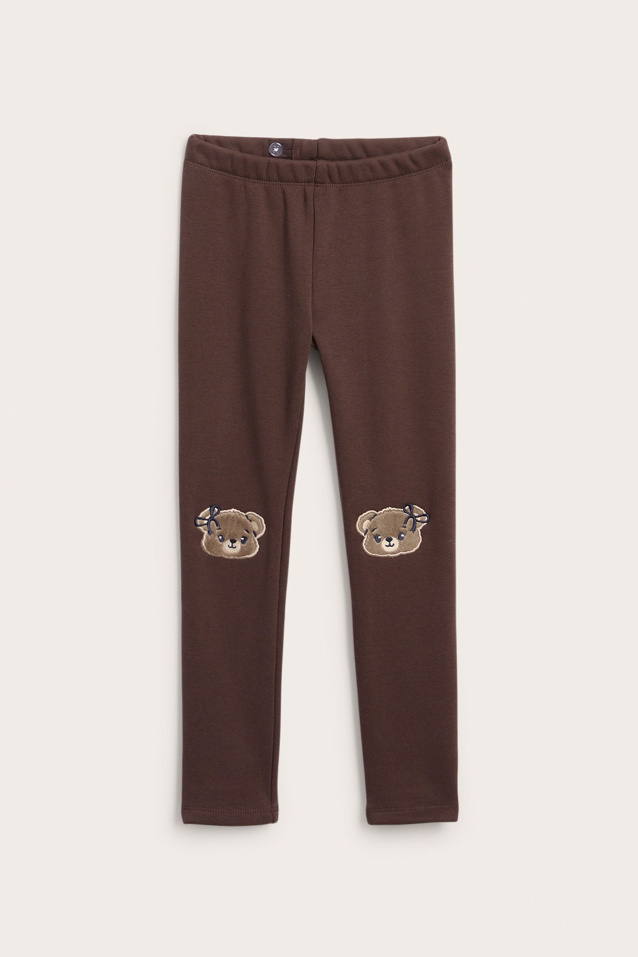 Frontvy av bruna barnleggings med broderade björnknälappar.