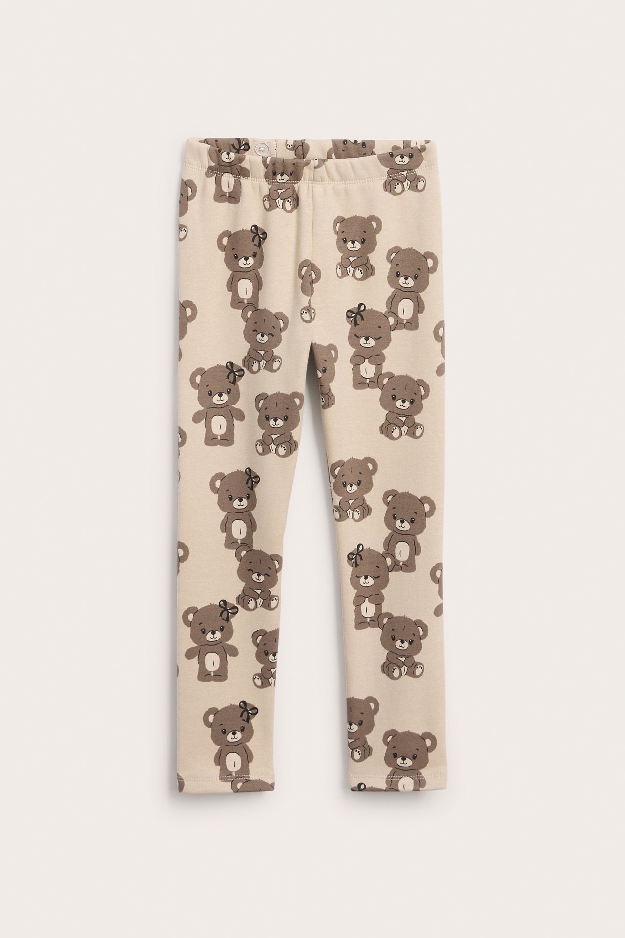 Barnleggings i beige med allover-tryck av nallebjörnar, framifrån.