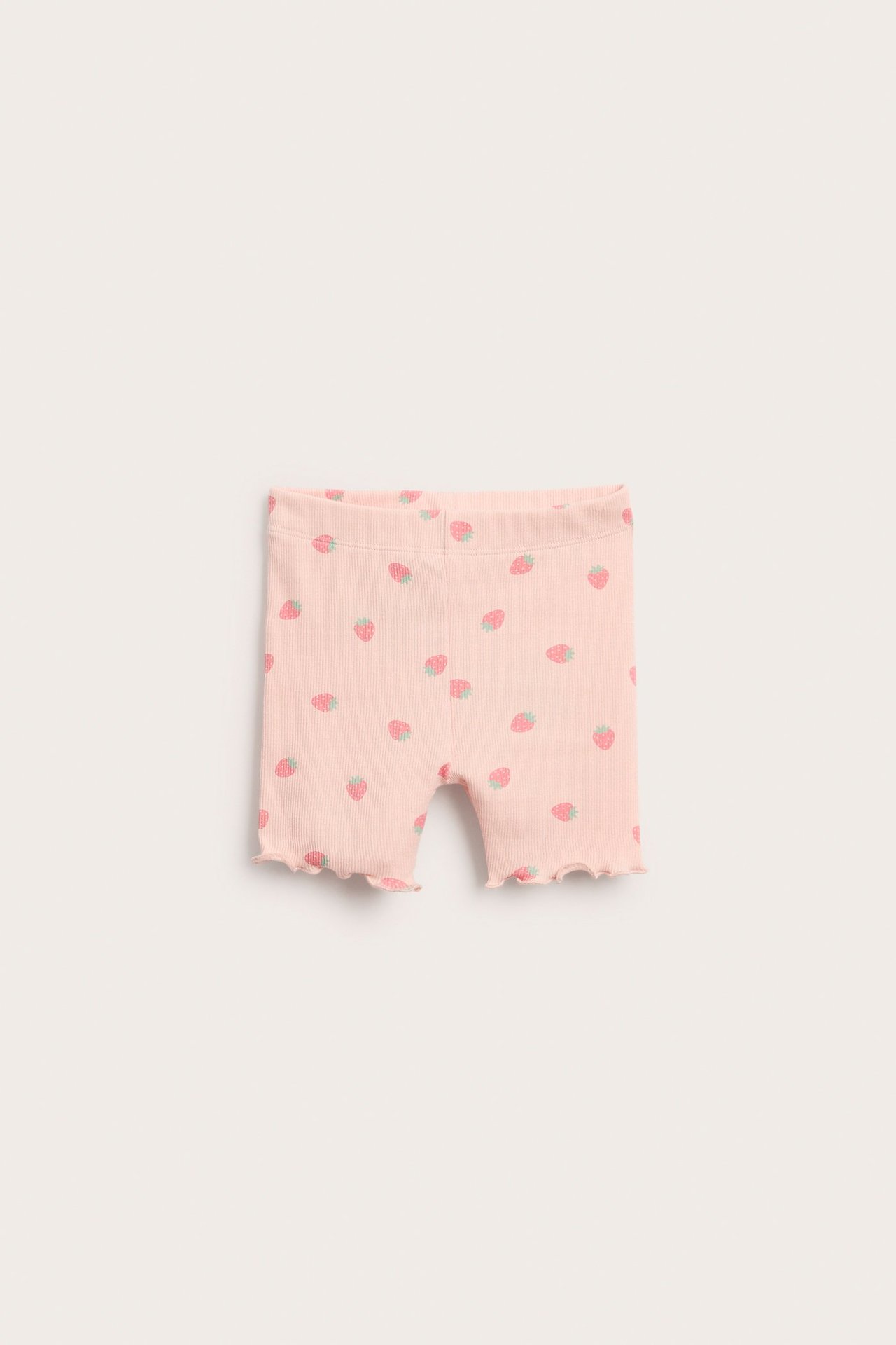 Widok z przodu, różowe prążkowane spodenki dla niemowląt z truskawkowym wzorem i falistymi brzegami.