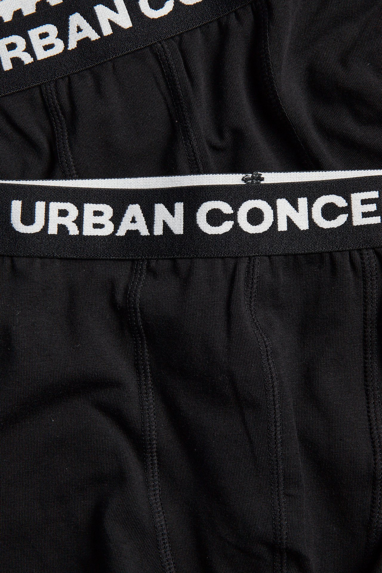 Lähikuva mustista alusvaatteista, joissa valkoinen 'URBAN CONCEPT' -logo vyötärönauhassa.