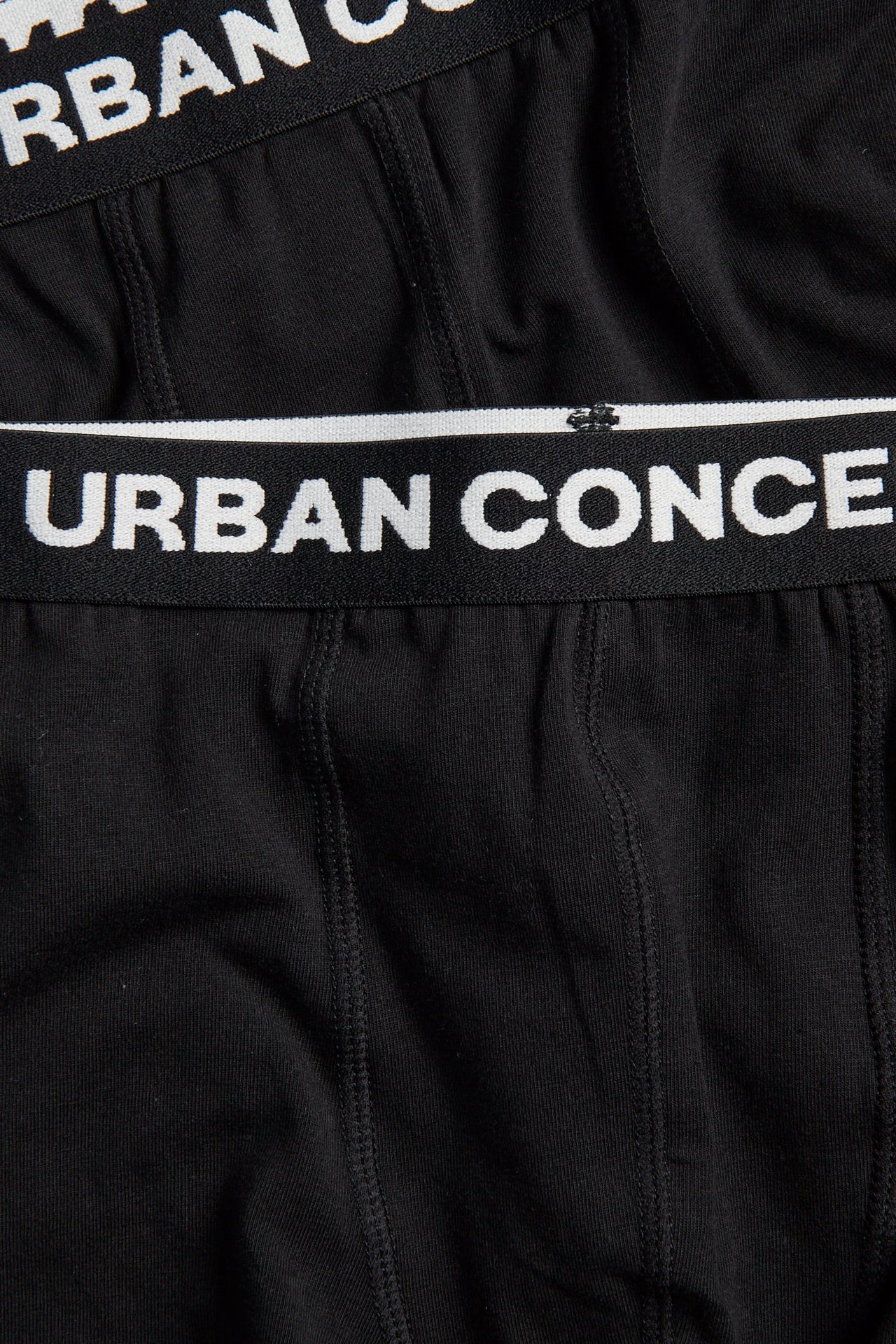 Lähikuva mustista alusvaatteista, joissa valkoinen 'URBAN CONCEPT' -logo vyötärönauhassa.