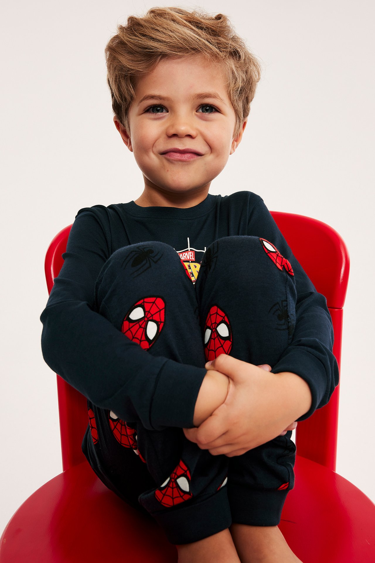 Barn i mørkblå langermet genser og pyjamasbukser med Spiderman-trykk, forfra.