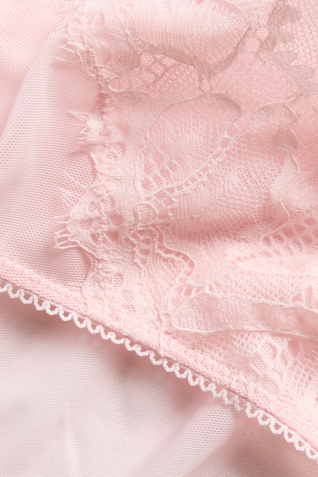 Nærbilde av rosa truse i blonde og netting med dekorativ picotkant.