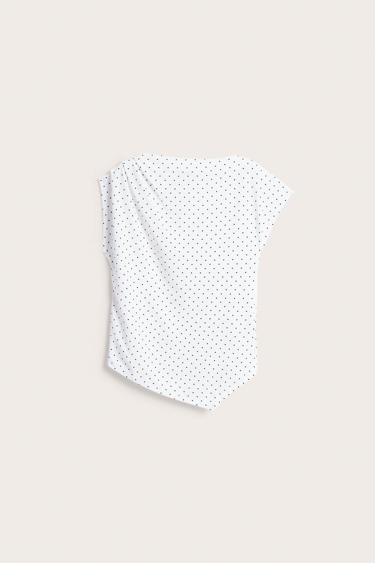 Edestä näkymä valkoisesta pilkullisesta epäsymmetrisestä topista lyhyillä hihoilla.