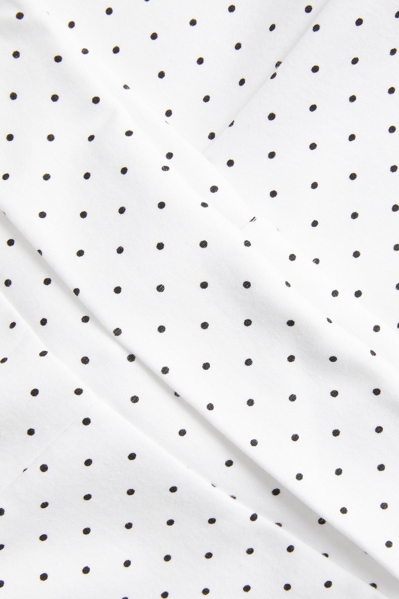 Zbliżenie na białą, kropkowaną dzianinę bawełnianą na spodnie do jogi.