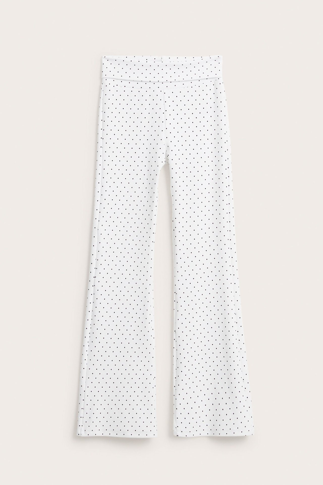 Edestä, valkoiset levenevät joogahousut pilkullista puuvillatrikoota taitettavalla vyötäröllä.