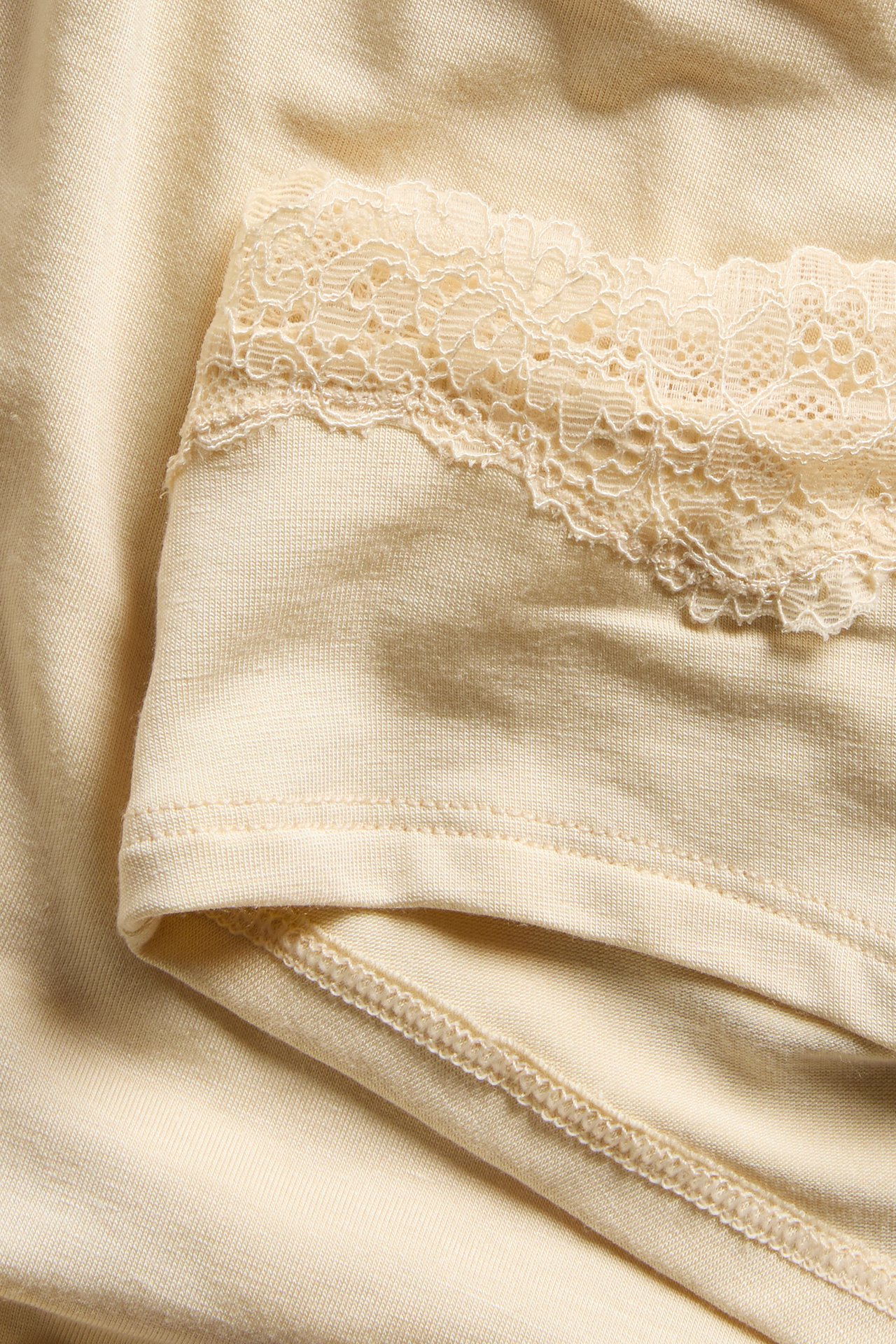 Närbild av beige cheeky trosa i modal med fin spetskant längs midjan.