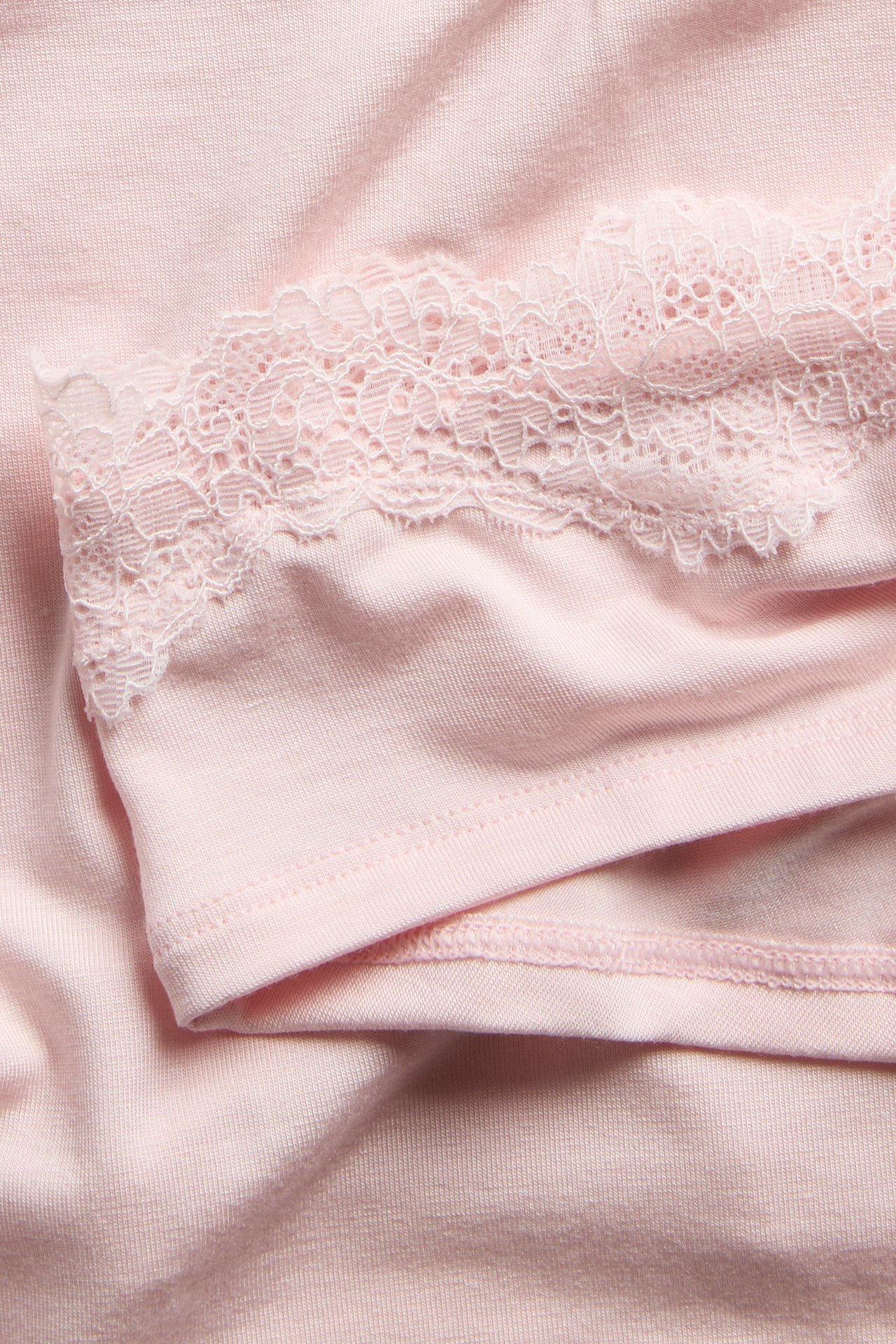 Närbild av ljusrosa cheeky trosa i modal med fin spetskant.