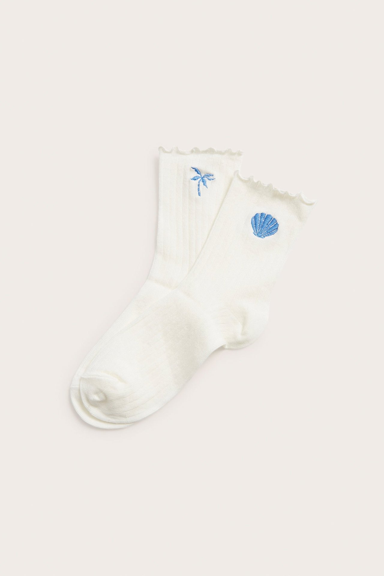 Ribbede offwhite sokker med volangkant, brodert med en blå palm og et sjøskjell.