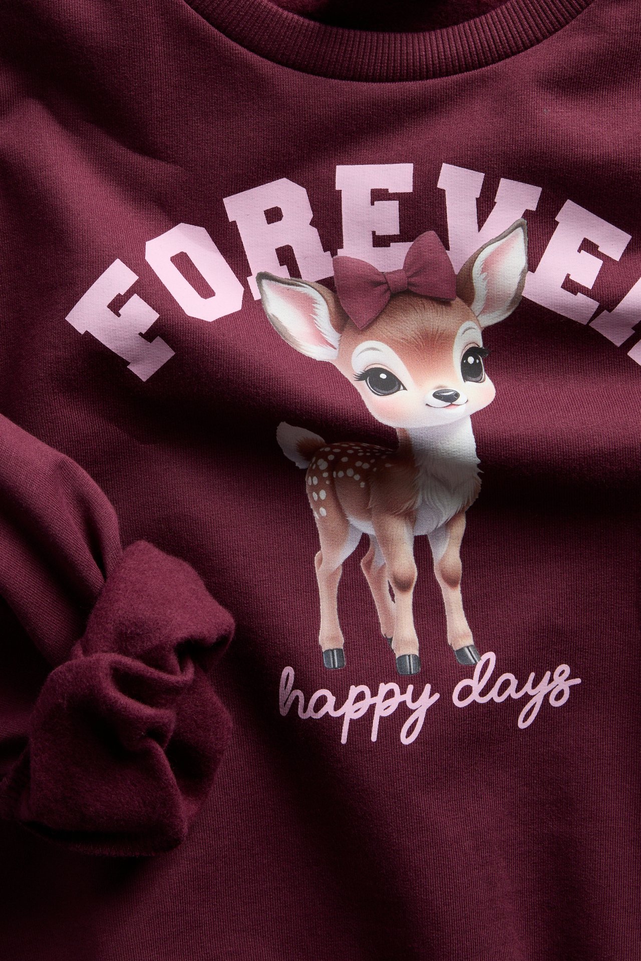 Widok z przodu blisko: bordowa dziecięca bluza z nadrukiem jelenia i 'FOREVER happy days'.