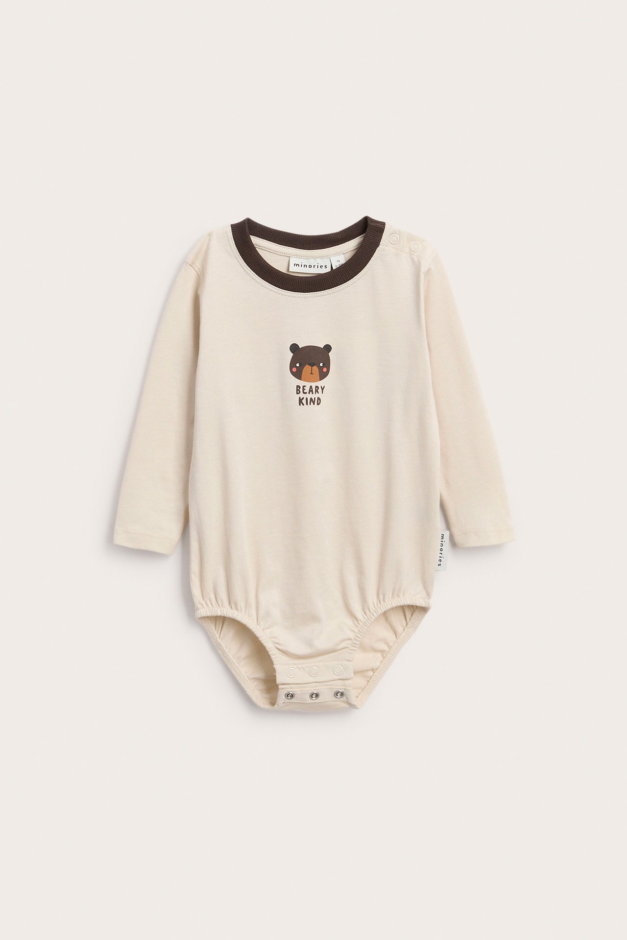 Edestä kuvattu kermanvärinen pitkähihainen vauvan body ruskealla karhupainatuksella ja 'BEARY KIND' -tekstillä.