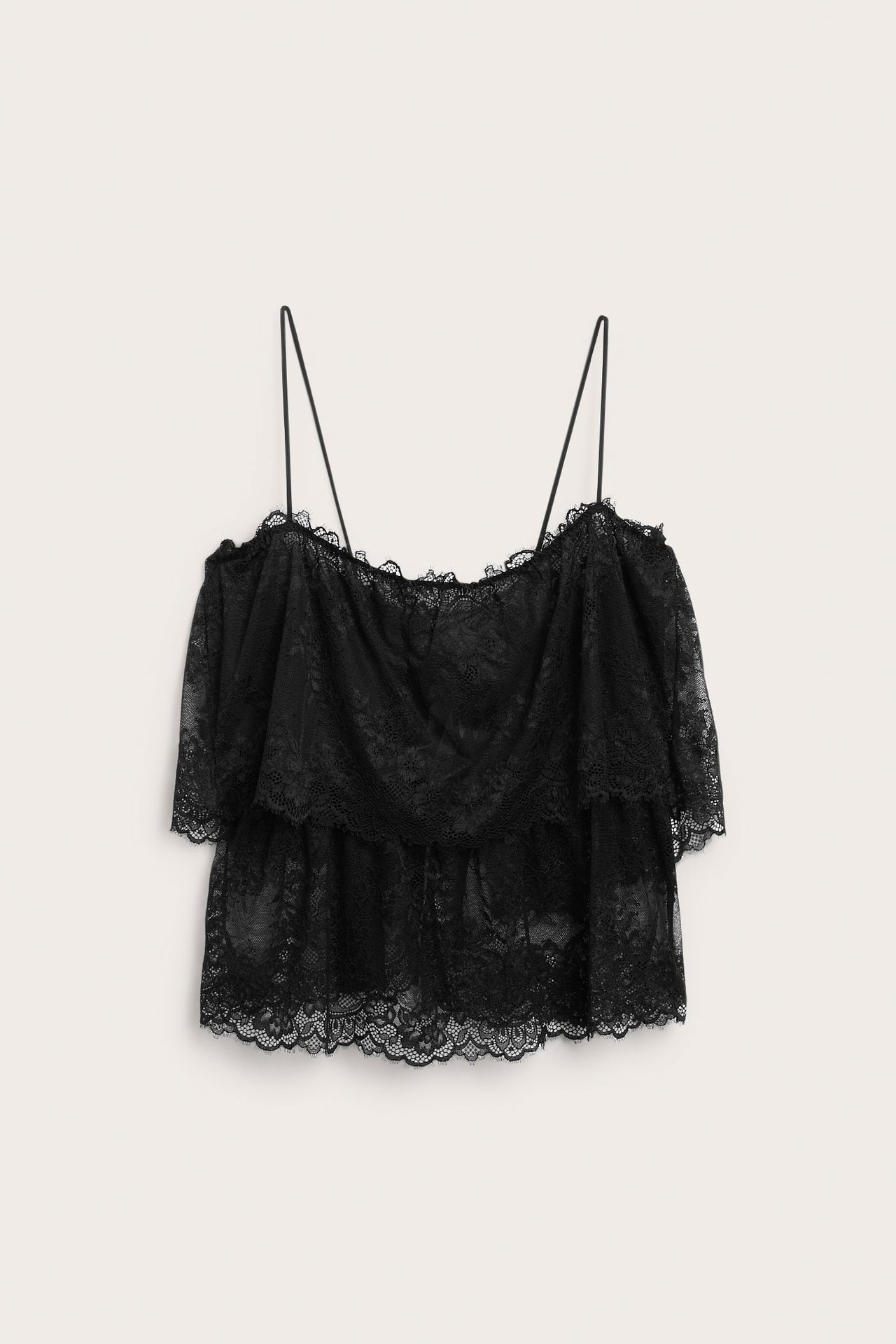 Edestä päin: musta pitsinen, kerrostettu off-shoulder-toppi spagettiolkaimilla.