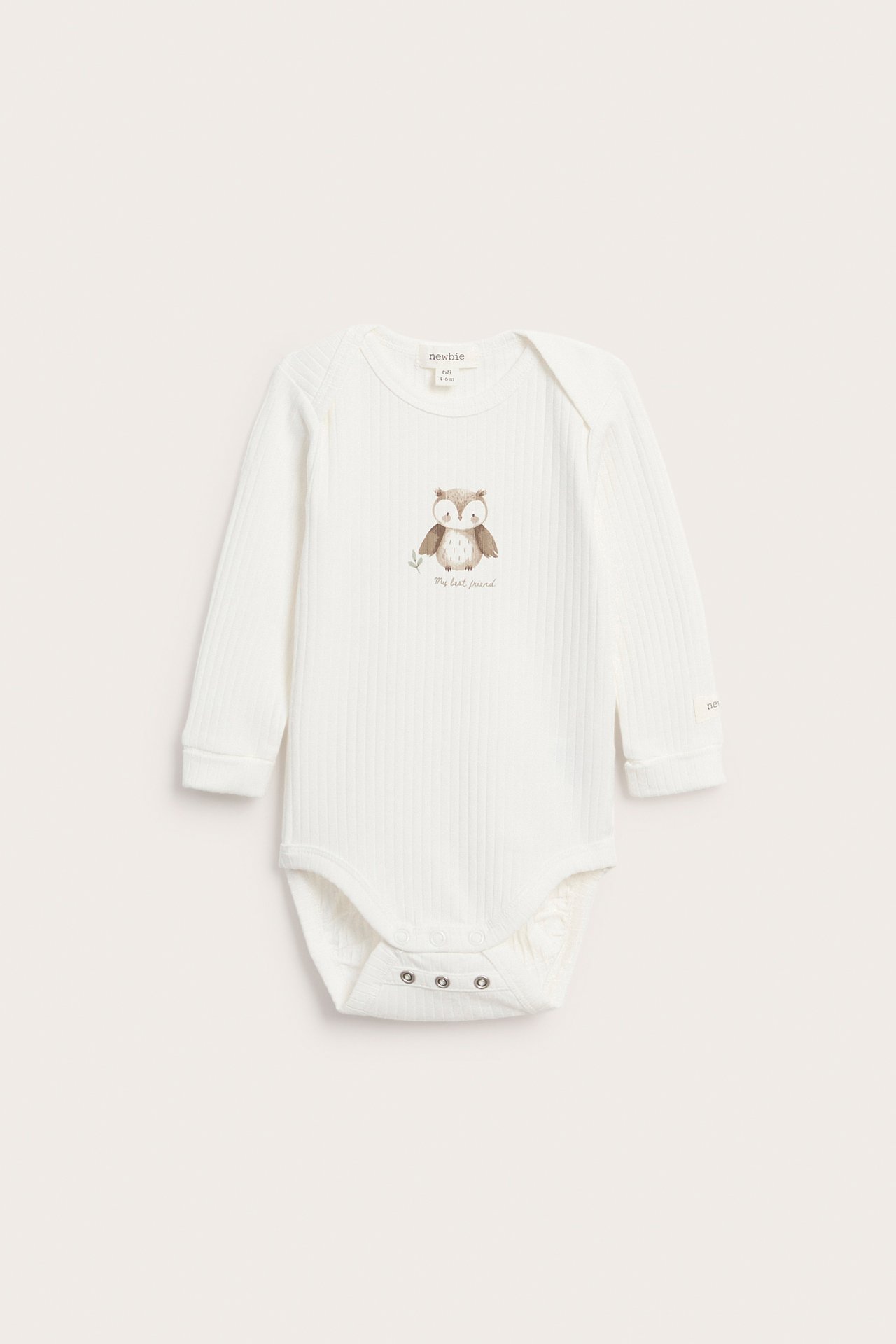 Frontbilde av en langermet, ribbet, offwhite babybody med ugletrykk og trykknapper.