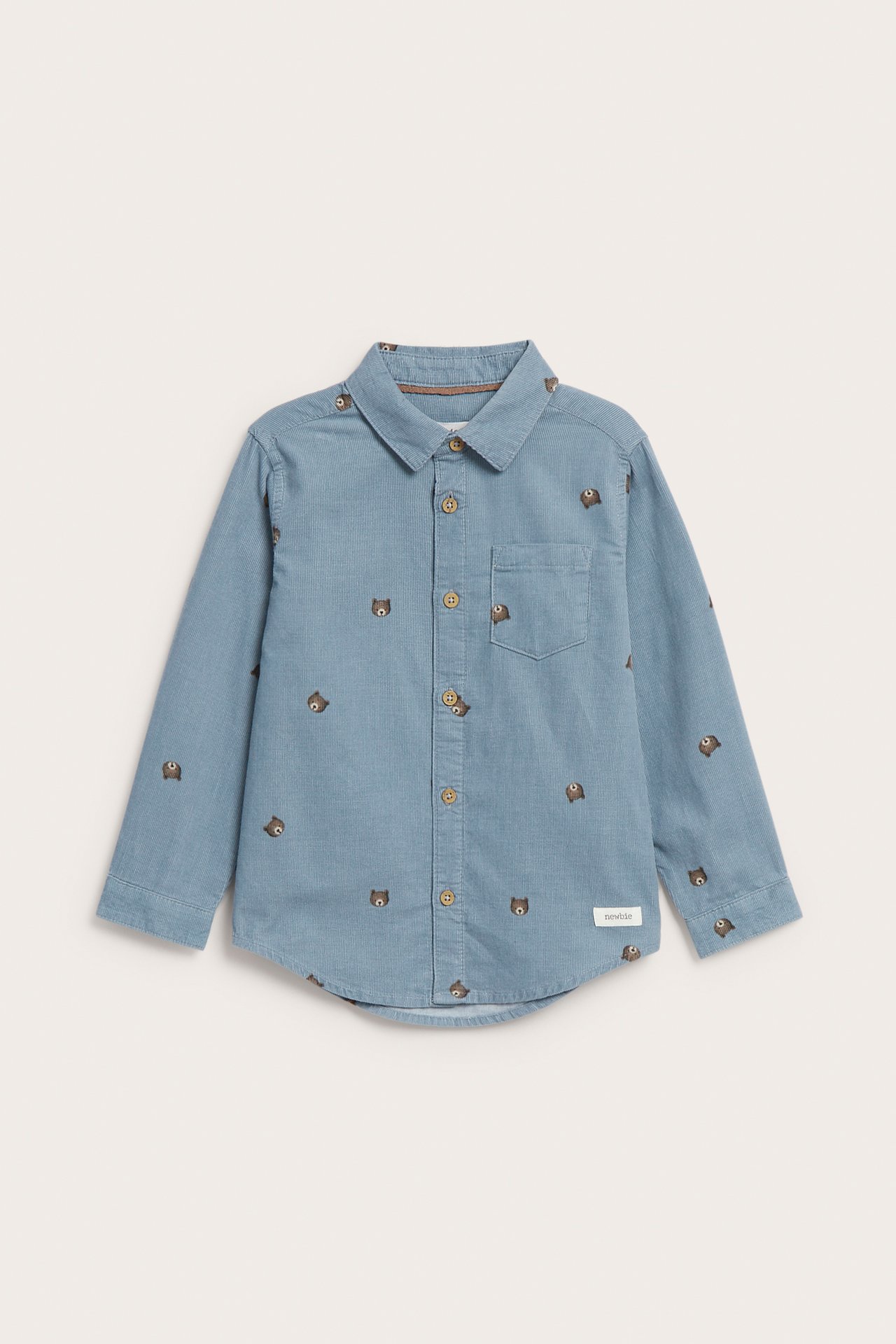 Framsida av en barnblå långärmad skjorta med broderade björnansikten och bruna knappar.