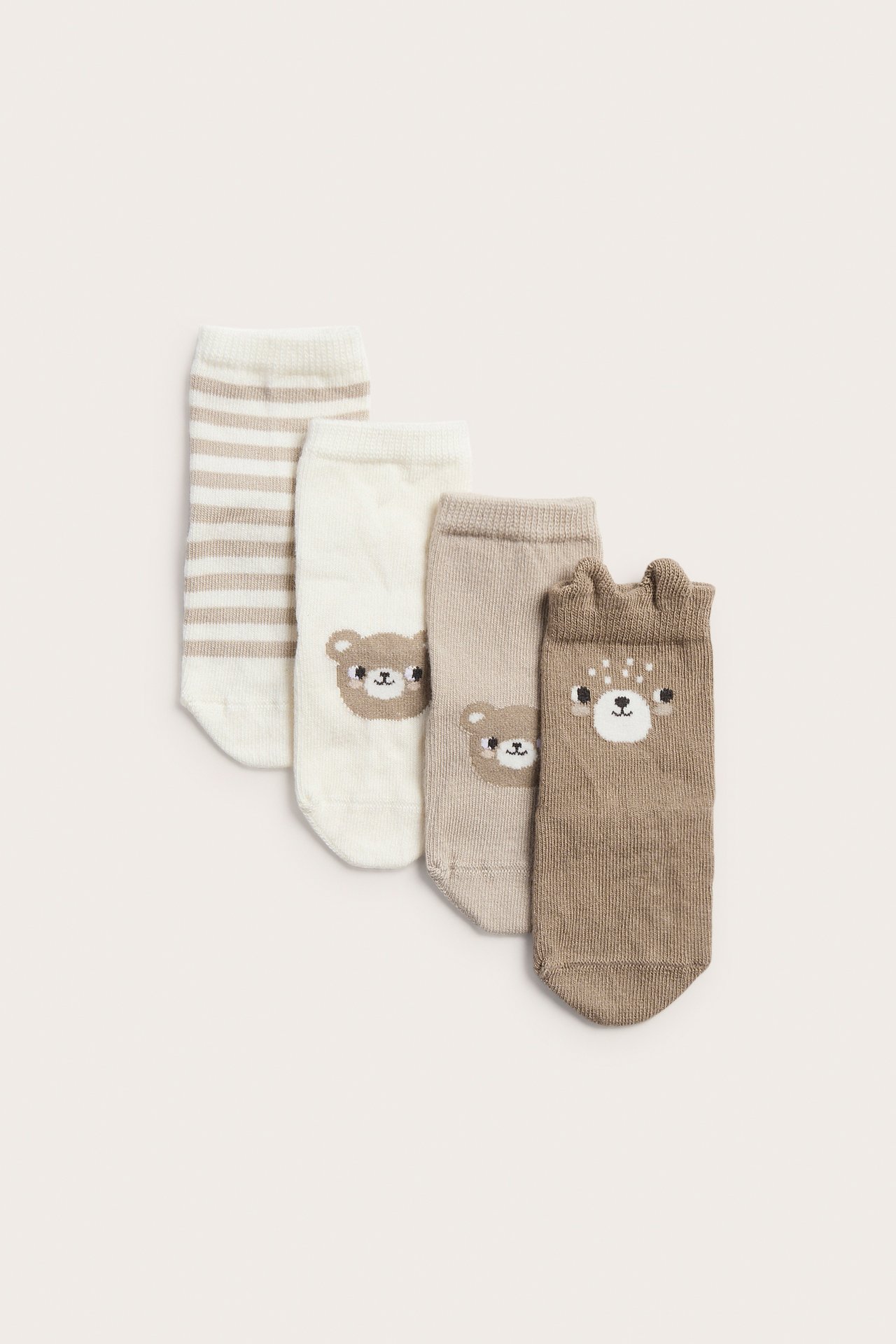 Ovanifrån fyra par babysockor: en randig, två med björnansikten, en med rådjursansikte.